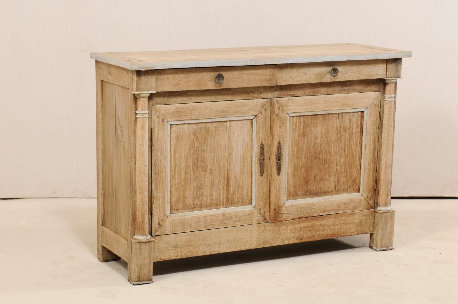 A French 4.5 ff long credenza cabinet from the early 19th century. This antique buffet cabinet from France has a rectangular-shaped top overhanging the body/case below which houses a pair of small half-drawers at top above a pair of recessed panel