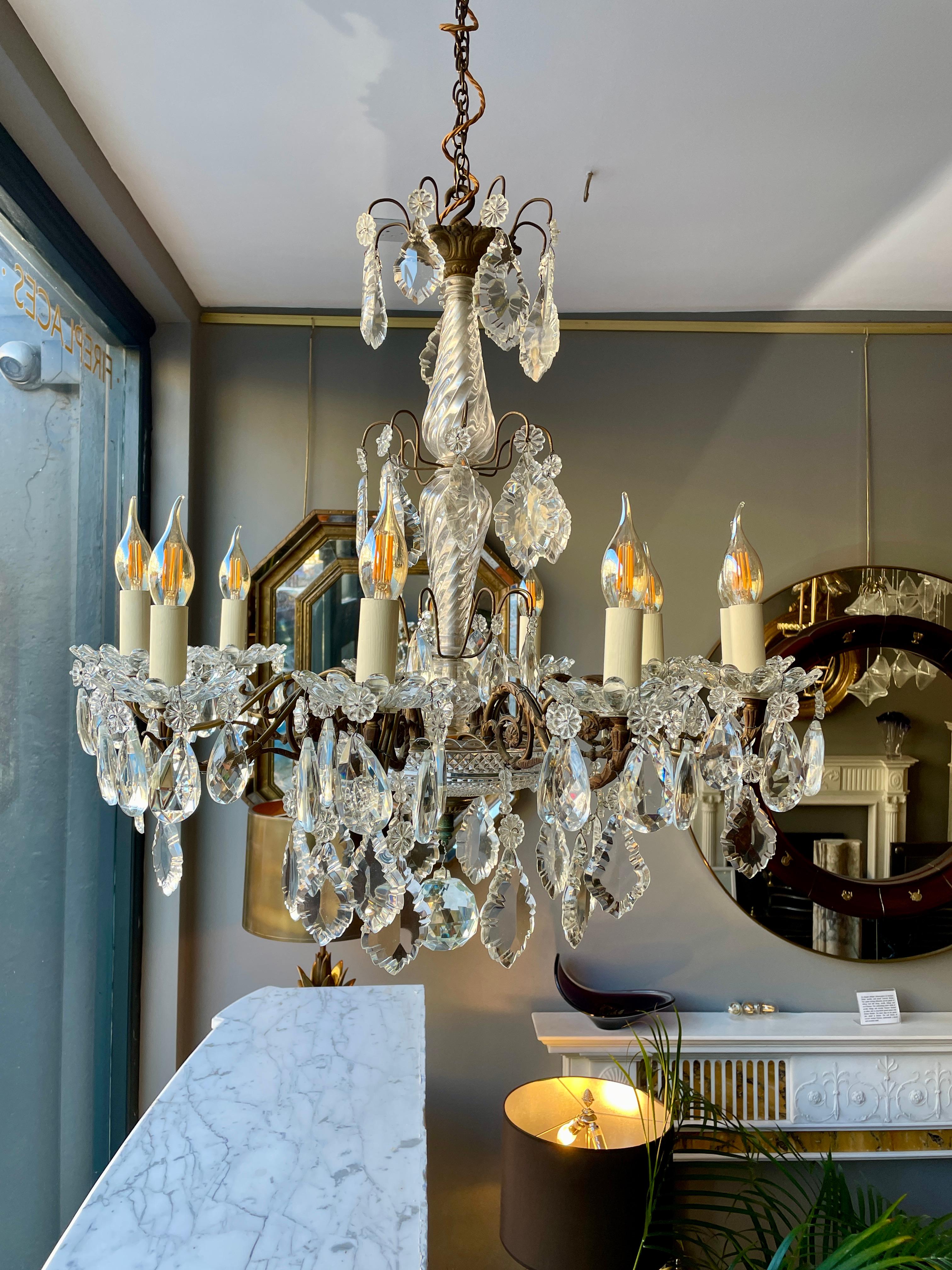An elaborate bronze and crystal 10 arm chandelier. The scrolled foliate bronze frame, decorated with lead crystal centre stem and faceted dish beneath with a large crystal ball centre drop. The foliate and faceted crystal drops in abundance. A very