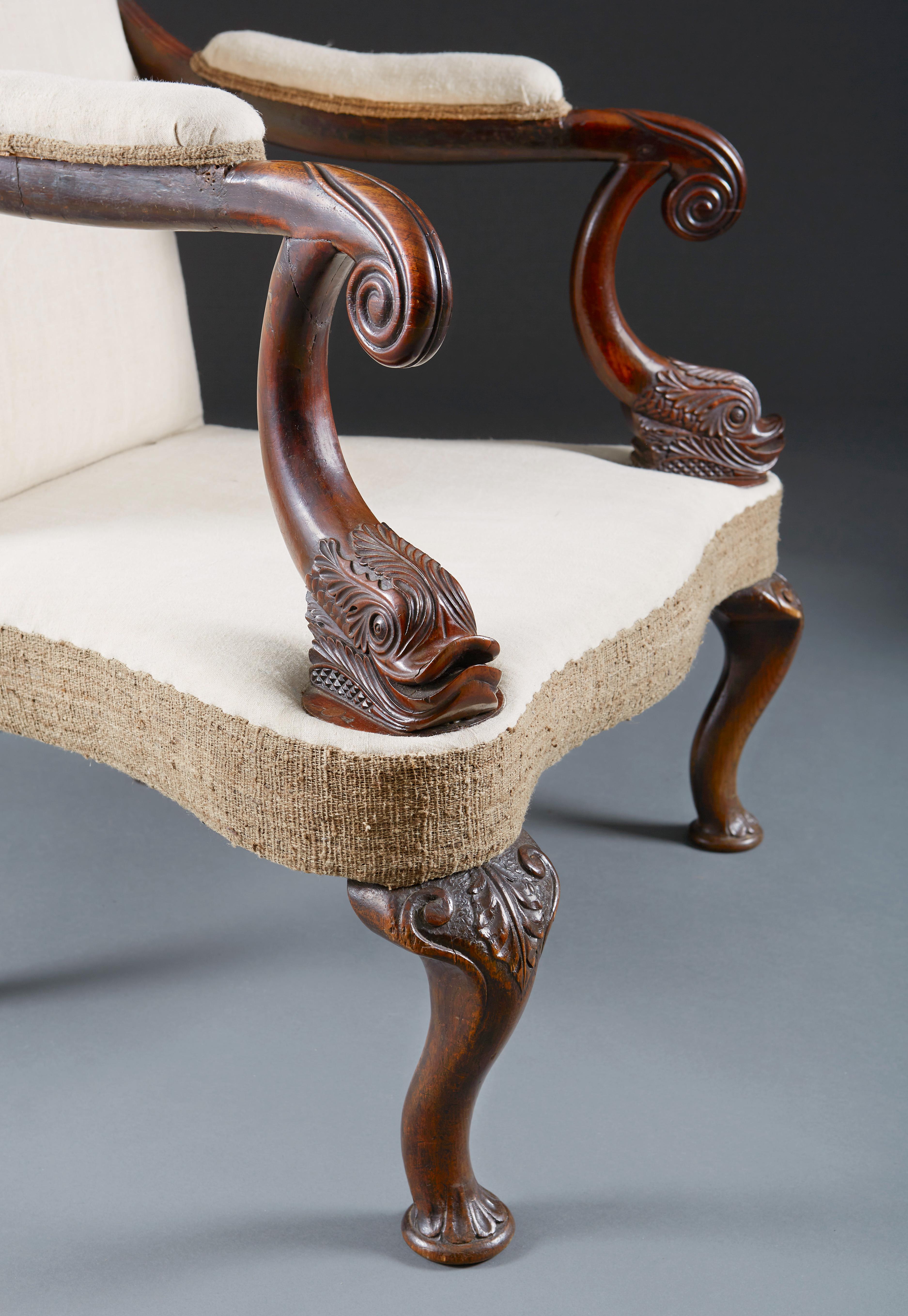A fine mid-19th century walnut library armchair with wing back and unusual dolphin carving to the arms, all supported on cabriole legs. Recently upholstered to calico with tufts.