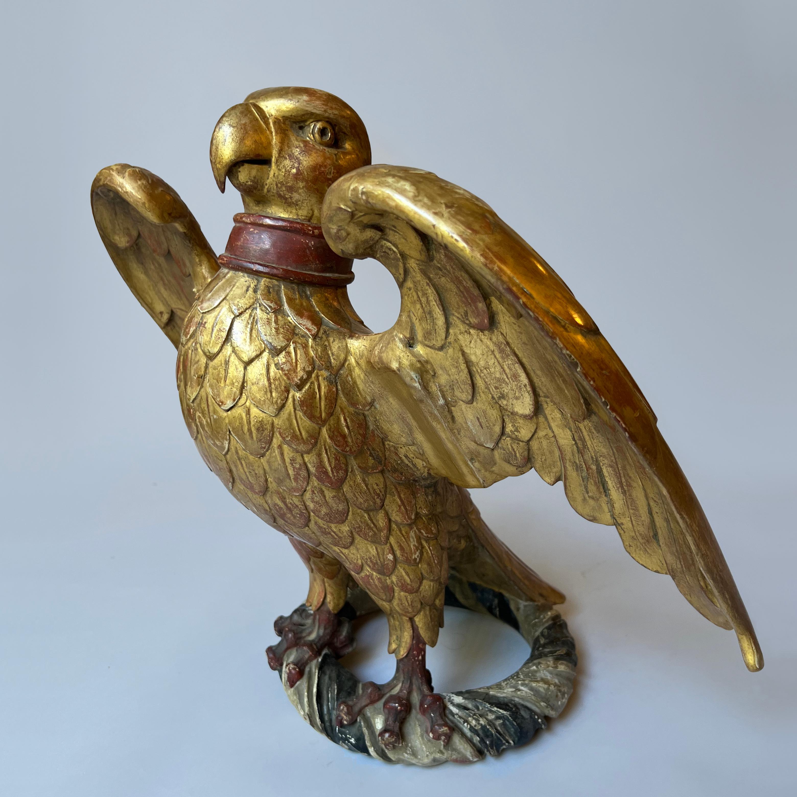 A finely carved C19th French Napoleonic giltwood eagle, modelled with outstretched wings, sitting on a carved circular painted base.