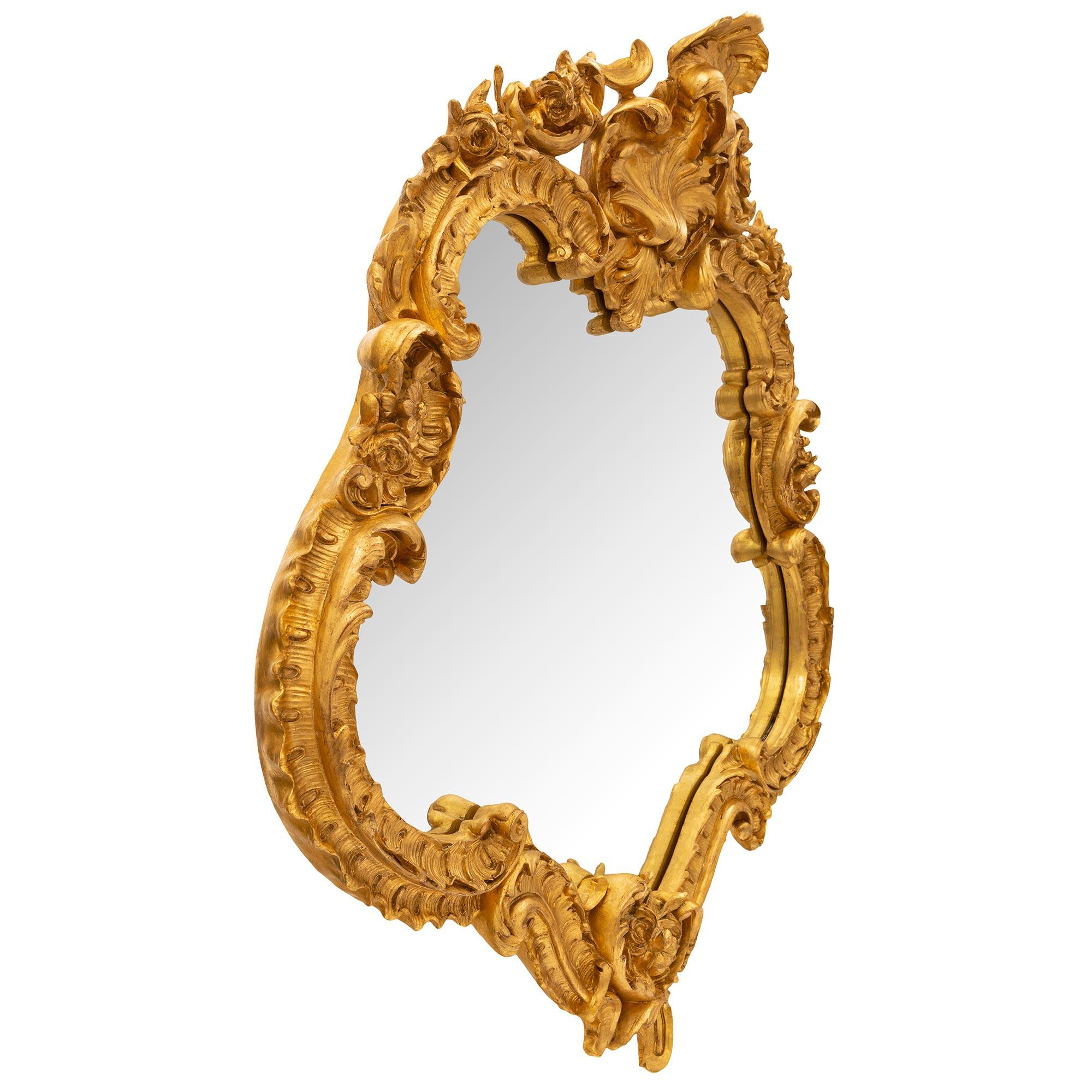 Eccezionale e unico specchio in legno dorato francese del XIX secolo Luigi XV. Lo specchio conserva la lastra originale incastonata in una cornice di legno dorato smerlato estremamente decorativa. La cornice mostra squisiti movimenti a voluta con