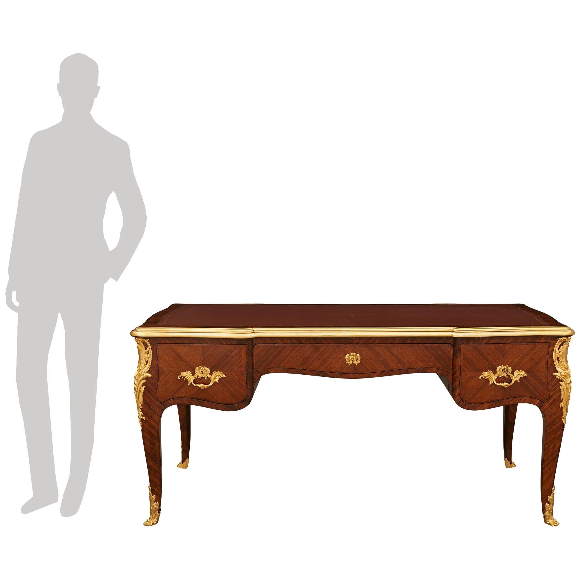 Impresionante y grandioso escritorio francés del siglo XIX, de estilo Luis XV, de madera de tulipán y ormolu. Este maravilloso escritorio Bureau Plat se eleva sobre cuatro hermosas patas cabriolé decoradas por la parte inferior con follaje de Ormolu