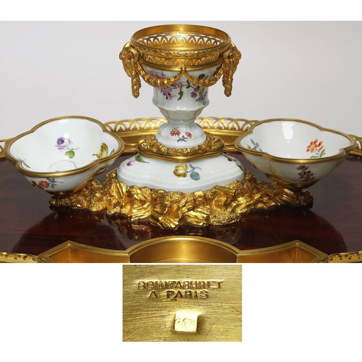 A very fine French 19th century Louis XV style gilt-bronze, mahogany and porcelain Encrier (Inkwell). The oval mahogany base surmounted with an ormolu mounted trim, dual-trays and figures of ram-heads with laurel wreaths on a centre porcelain