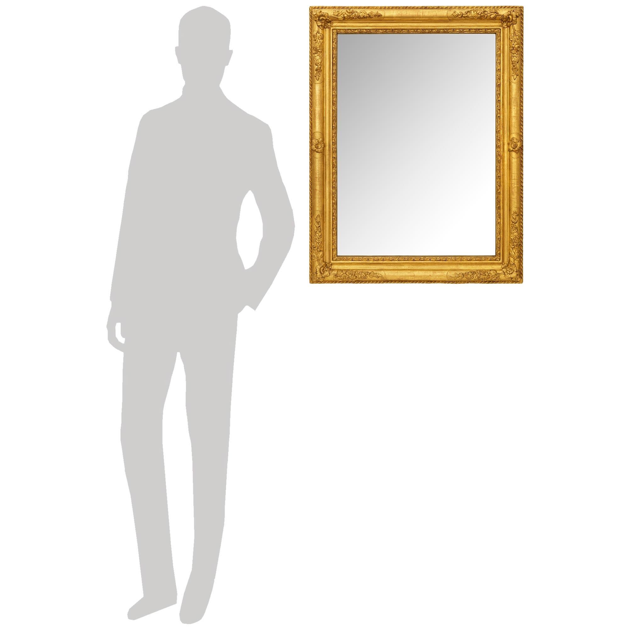 A charming and high quality French 19th century Louis XV/XVI st. Giltwood mirror. This most elegant rectangular mirror can be placed vertically or horizontally, while displaying an intricately detailed twisted rope design on the perimeter. The inner