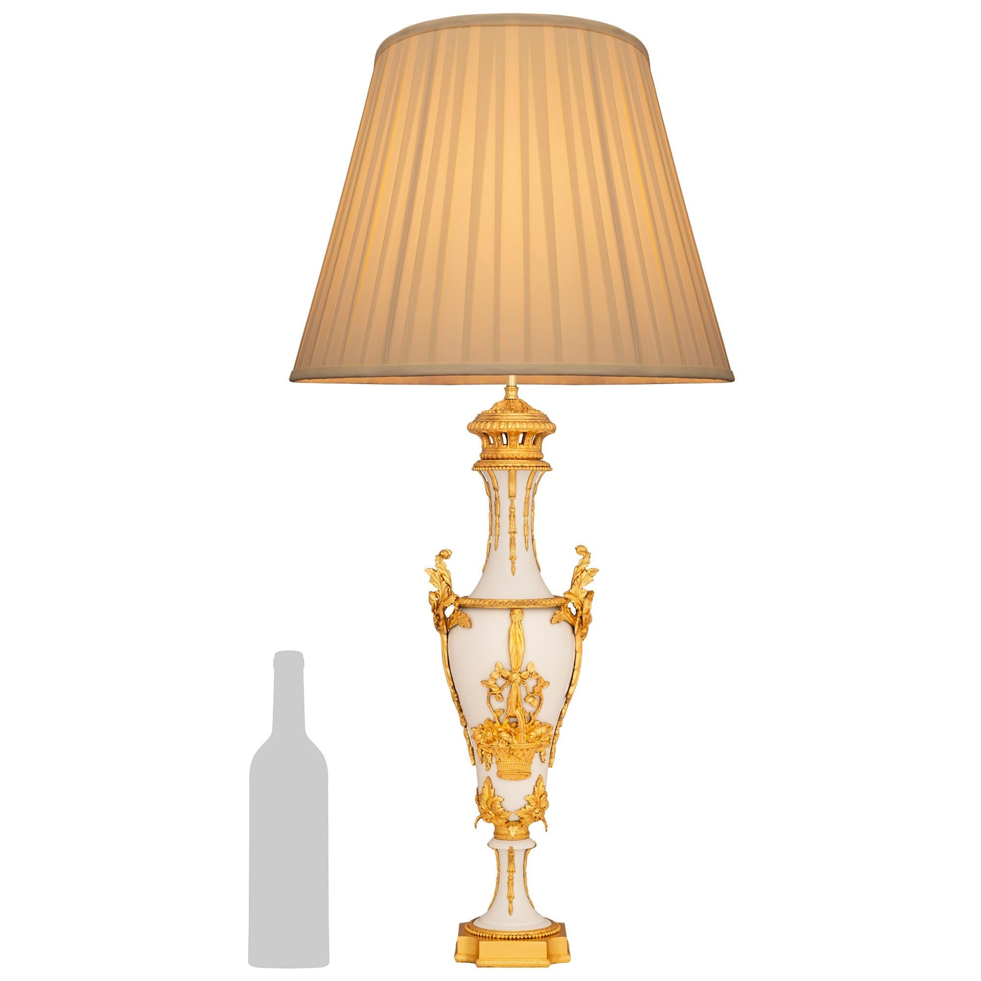Una splendida e decoratissima lampada francese del XIX secolo in porcellana biscuit e Ormolu del XIX secolo. Questa lampada molto attraente si erge su una base quadrata in Ormolu con angoli concavi e una base a reticolo screziato con motivi di