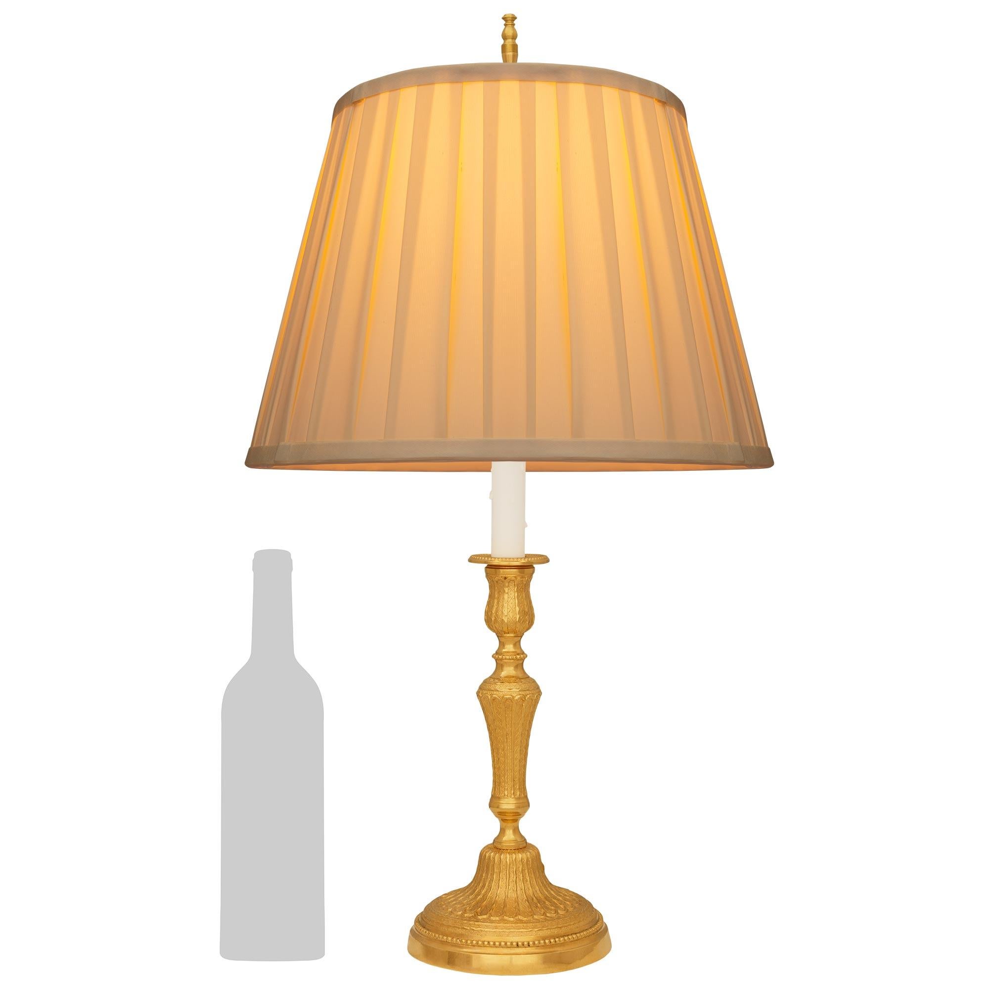 Eine elegante französische Ormolu-Lampe aus dem 19. Jahrhundert im Stil Louis XVI. Dieser charmante, zu einer Lampe montierte Kerzenständer wird von einem runden Ormolu-Sockel mit gesprenkeltem Rand und einem äußeren Perlenband getragen. Die Mitte