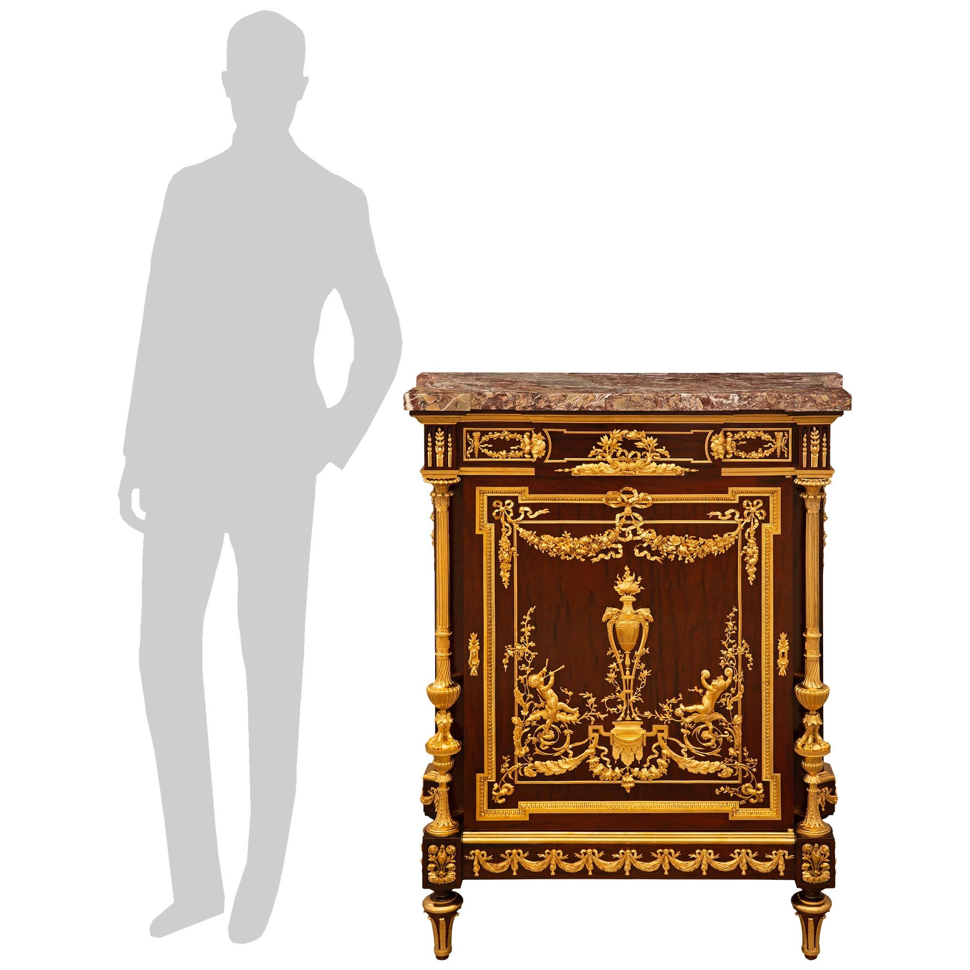 A stunning and exceptional quality French 19th century Louis XVI st. Ormolu, Mahogany, and Rosso Levanto marble cabinet, signed by P. Sormani. This eye catching single door cabinet is raised by four topie shaped mahogany feet accented by slender