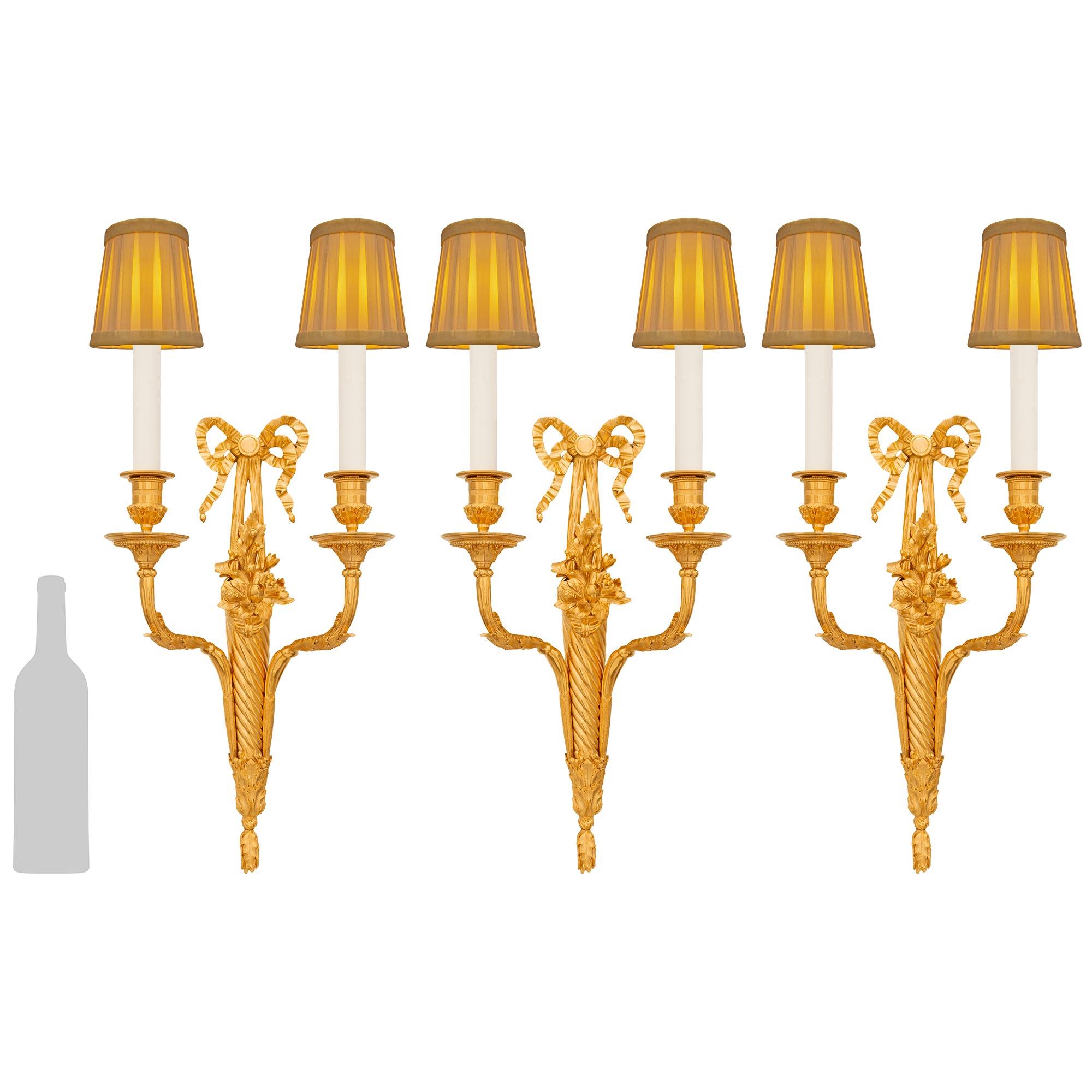 Un set estremamente elegante di tre appliques francesi del XIX secolo in stile Luigi XVI. Ciascuna applique a due bracci è centrata da un bellissimo fregio foliato al di sotto del supporto centrale ritorto. Ogni braccio a 