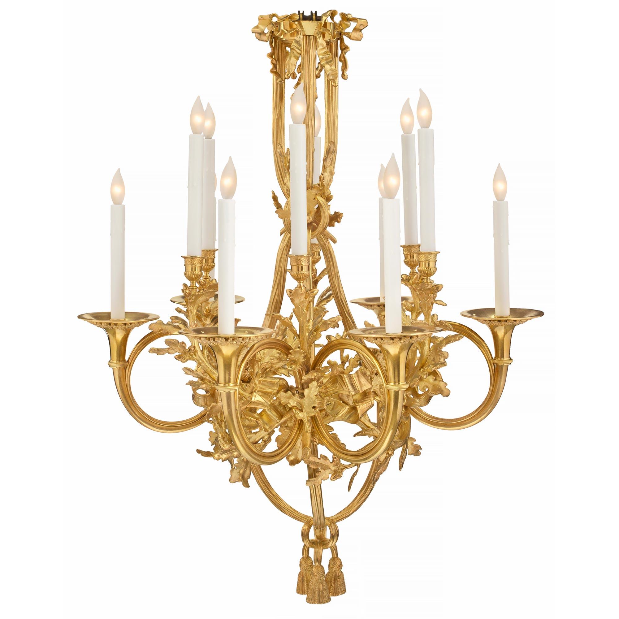 A spectacular French 19th century Louis XVI st. ormolu twelve light chandelier. The top of the chandelier has three richly detailed bows with ribbons flowing down and tied at the mid-section by acorn leaves. The ribbons continue downwards to a