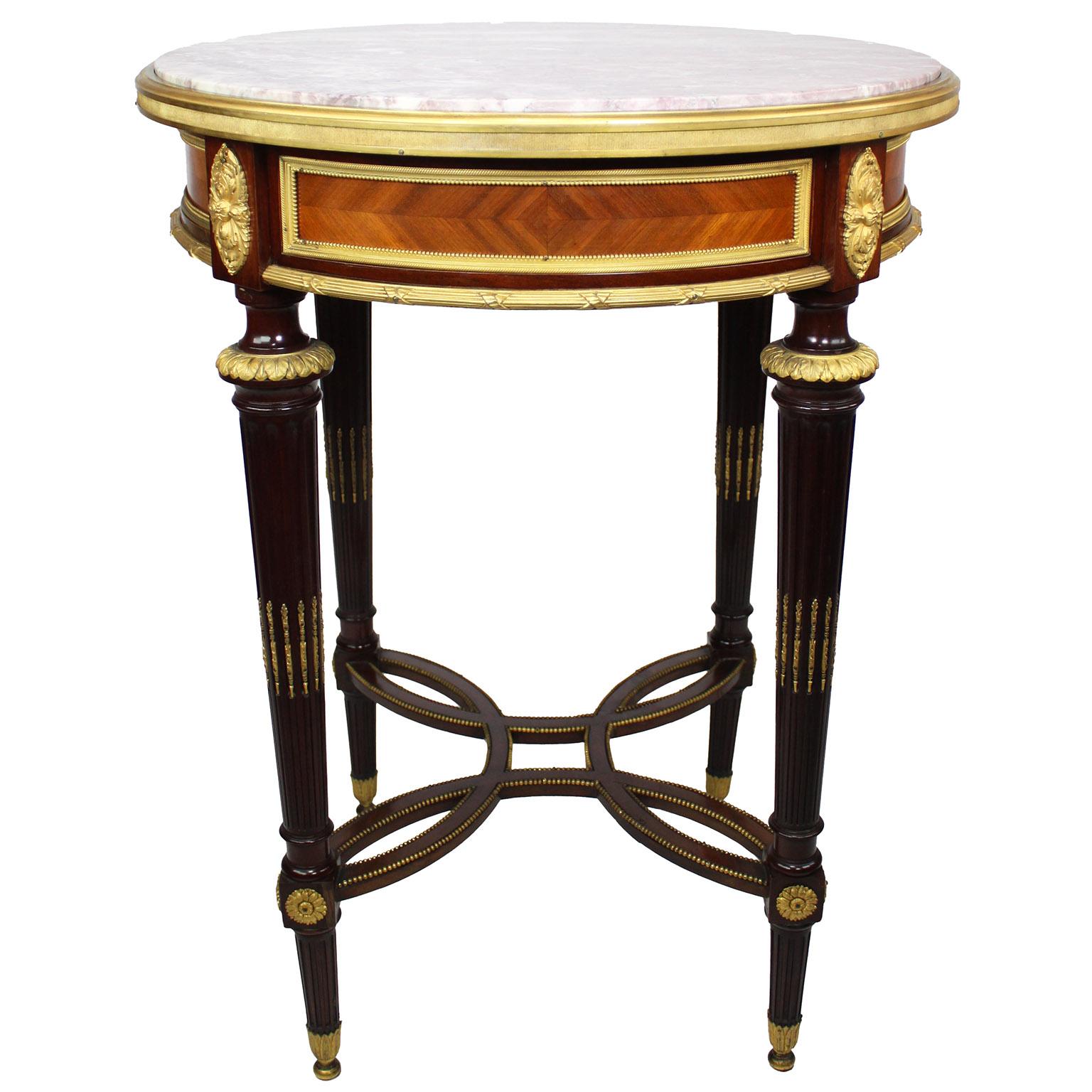 Très belle table ronde de style Louis XVI en acajou et bois de satin avec dessus en marbre, attribuée à Henry Dasson (français, 1825-1896). La table circulaire à un seul tiroir est dotée d'un plateau en marbre Brêche Violette encastré, entouré de