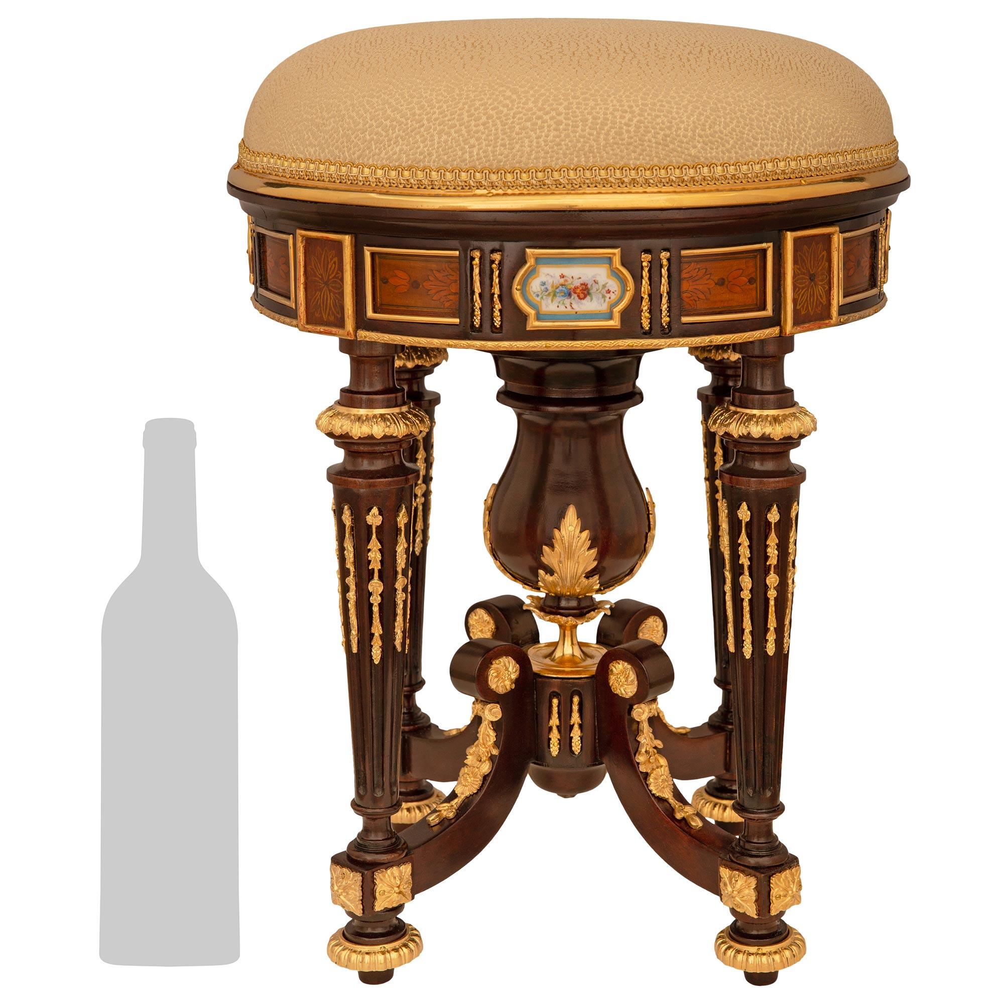 Un attrayant et très impressionnant banc de toilette/piano en acajou, bois fruitier, bronze doré, bois doré et porcelaine d'époque Louis XVI du 19e siècle. Ce banc finement détaillé repose sur quatre pieds cannelés et effilés en acajou et est