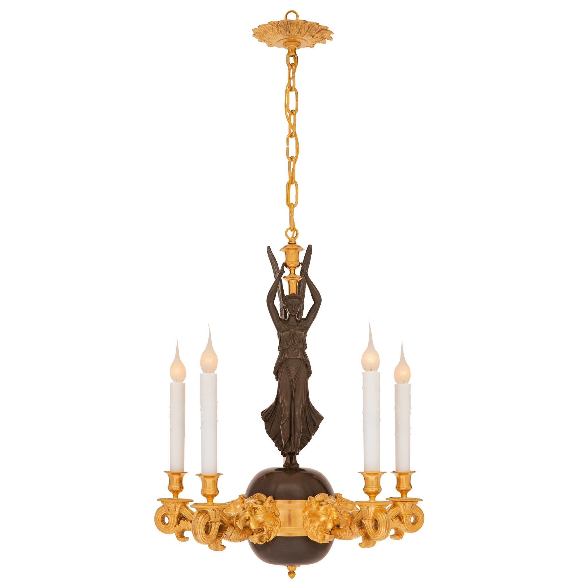 A beautiful and unique French 19th century Neo-Classical st. patinated bronze and ormolu chandelier. The five arm chandelier is centered by a striking patinated bronze ball with a fine bottom acorn finial and an impressive richly chased open winged