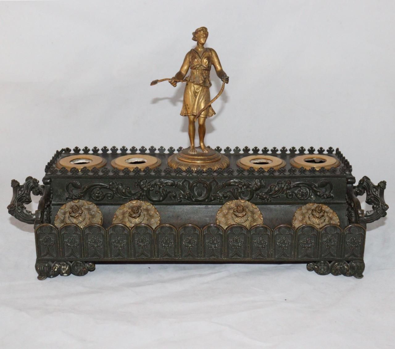 Diana the Huntress 
A Louis Philippe Neo-Gothic Style Ormolu Inkwell
Rectangular in brown patina bronze and gilt bronze. 
The tier presents in its center a statuette of Diana the Huntress and four receptacles for powder and ink on either side.