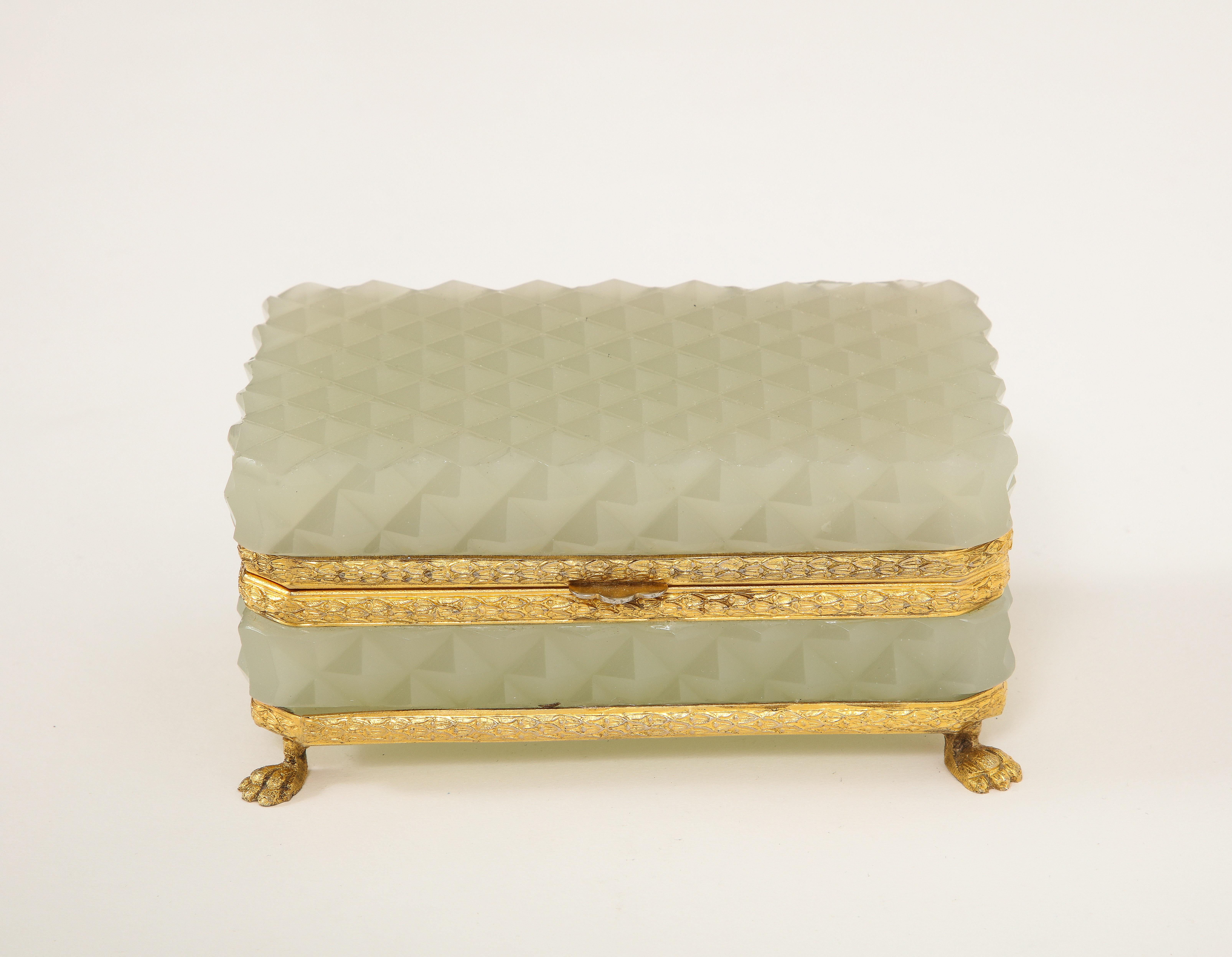A French 19th century Louis XVI Style Ormolu Mounted and Footed Prismic Pattern Cream Opaline Crystal Box. The box is composed of two sections of French prismic pattern cream opaline crystal which are mounted to a fabulous dore bronze latch and dore