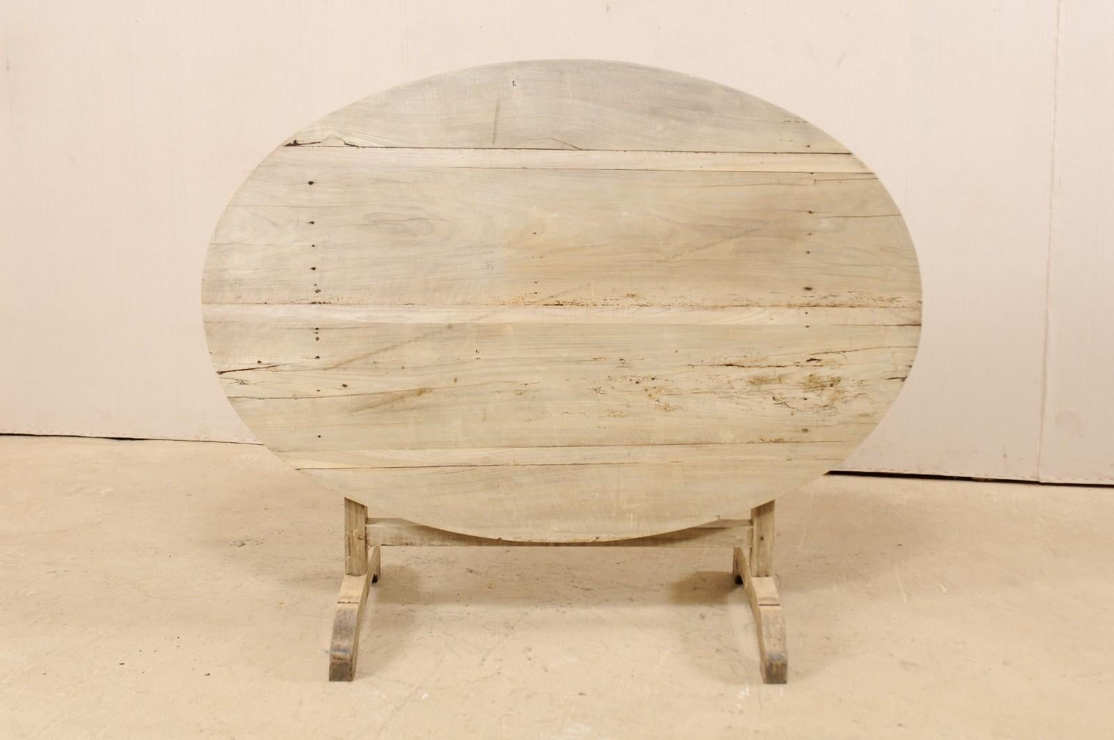 A French wine tasting table from the 19th century. This antique oval-shaped table from France features a tilt top, which is the signature of wine tasting tables during this time. When in use, the top is supported with a butterfly wedge, which turns