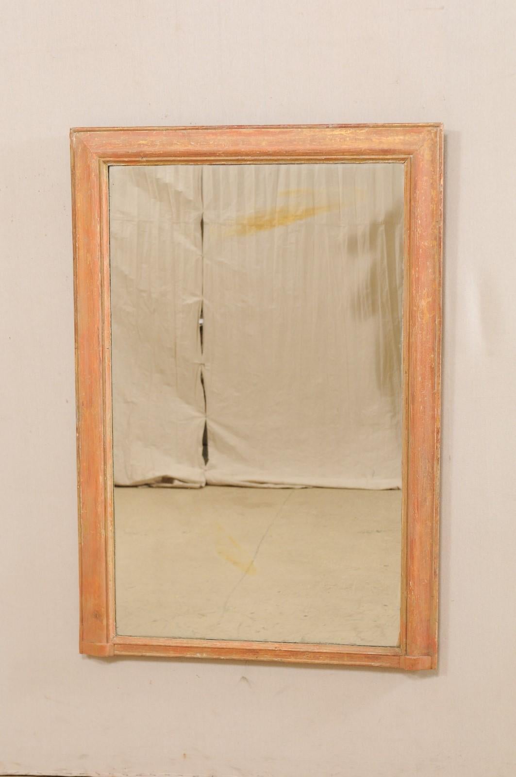 A French painted wood mirror from the 19th century. This antique mirror from France features clean, simple lines about the painted wood frame, with inner mirror being original. The primary coloring in this piece is a lovely salmon color, with an