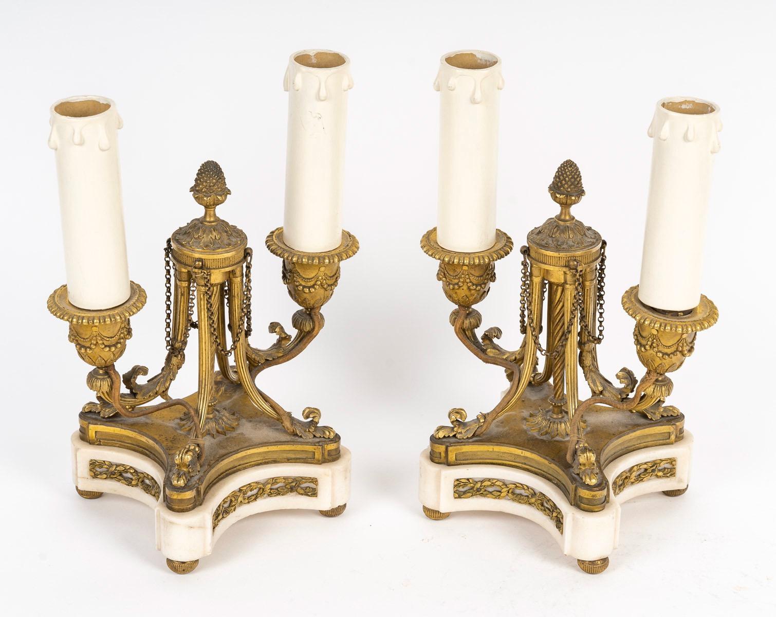 Una coppia di candelabri francesi del XIX secolo in stile Luigi XVI 

Due candelabri in bronzo molto finemente cesellato e dorato con due rami scanalati, la canna attorcigliata da cui fuoriescono in alto quattro catenelle, sormontate da una