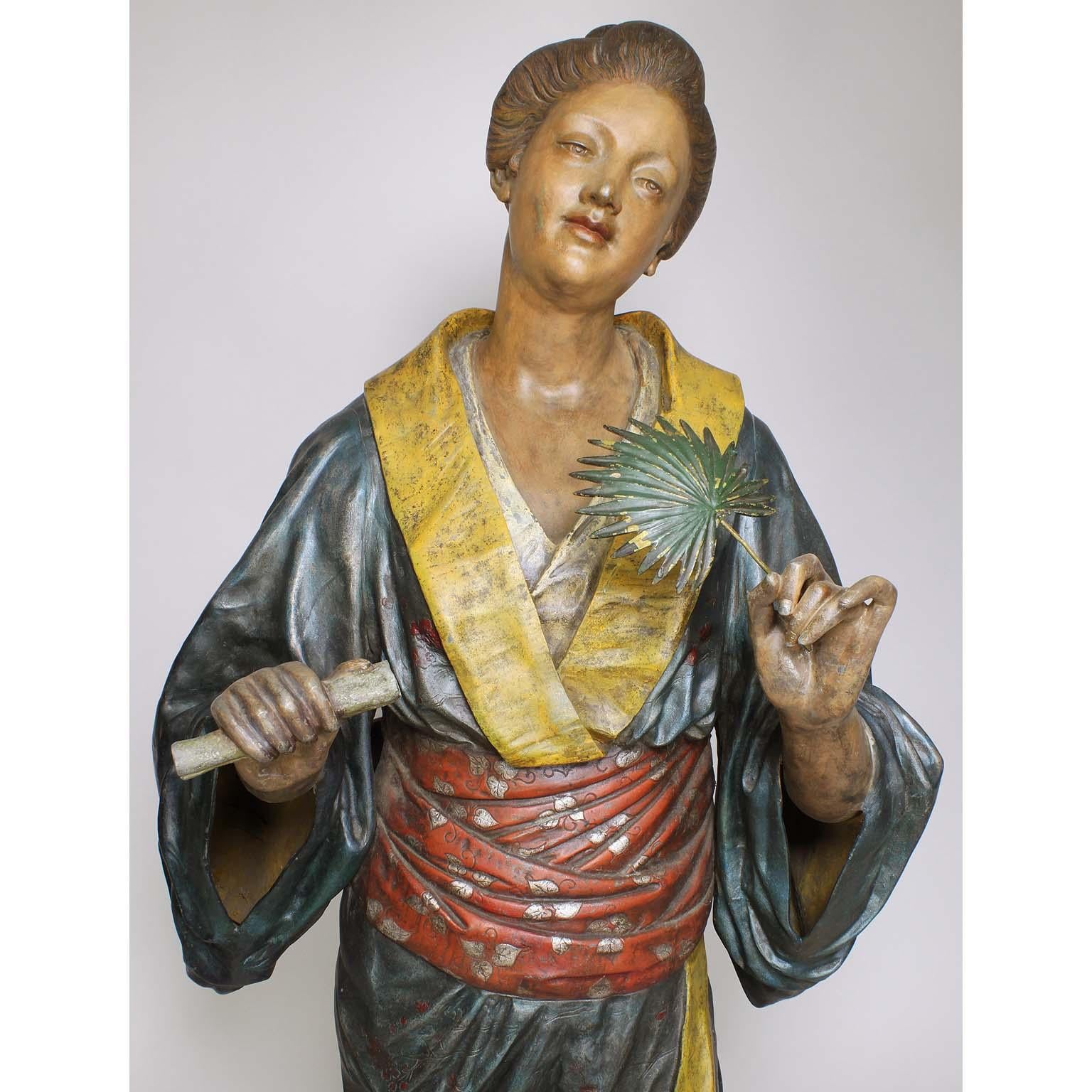 A fine French 19th century Polychromed Japonisme life-size cast-metal figure of a standing Geisha, cast after a model by Charles Massé (French, 1855-1913). The standing Japanese beauty wearing a flowing Kimono with both hands raised, holding a palm