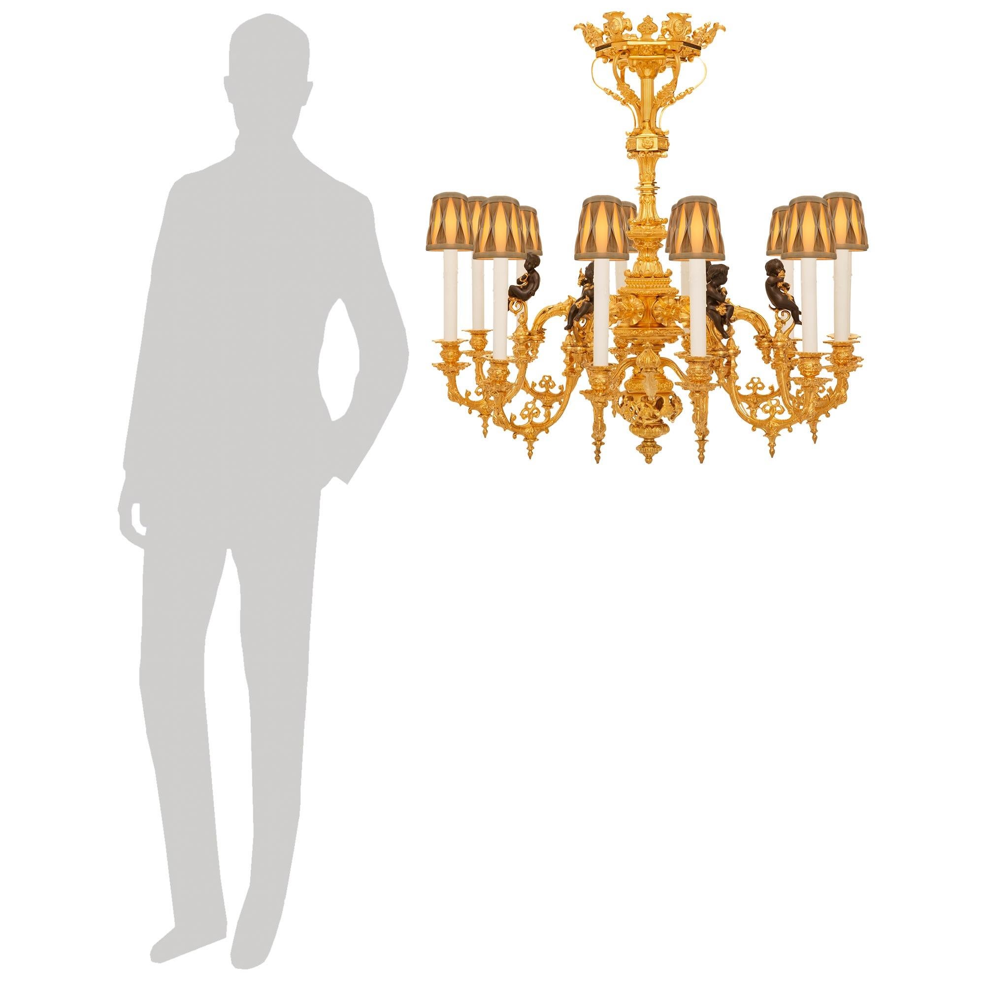 Uno splendido lampadario francese del XIX secolo in stile rinascimentale, in ormolu e bronzo patinato. Questo imponente lampadario a dodici bracci è incentrato su un terminale inferiore a forma di topie che pende sotto una base circolare traforata e