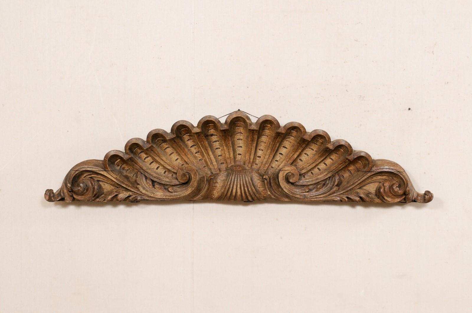 A French carved wood wall fragment from the 19th century. This antique wall decoration from France has been hand-carved, resembling a shell with an elaborate scallop-shaped top with scrolling acanthus leaves flanking either far side. This plaque has