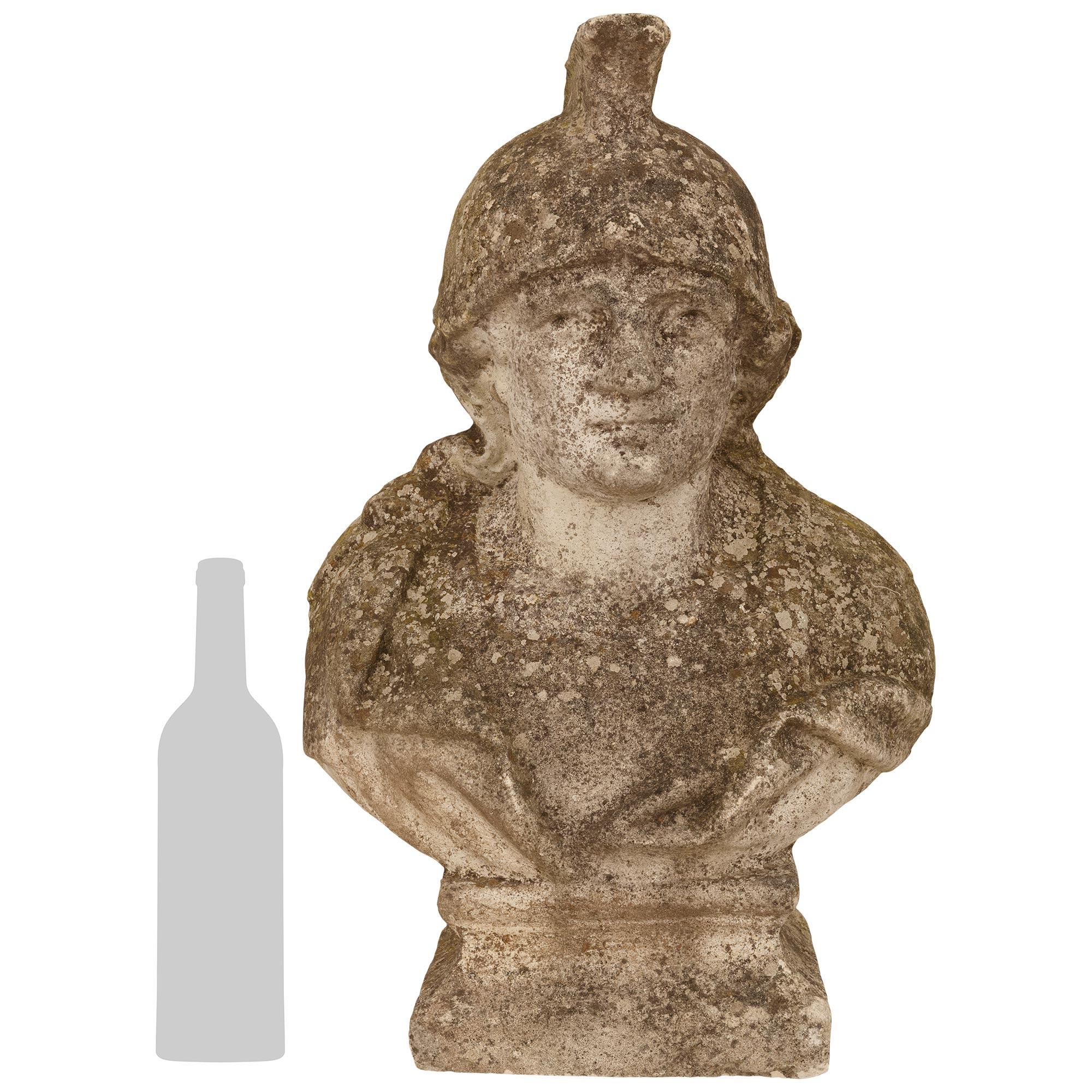 A charming French 19th century Stone warrior statue. This charming Stone statue of a warrior wearing his helmet is raised on a square base with a mottled edge. He wears a coat displaying detailed folds while displaying a attractive expression. All