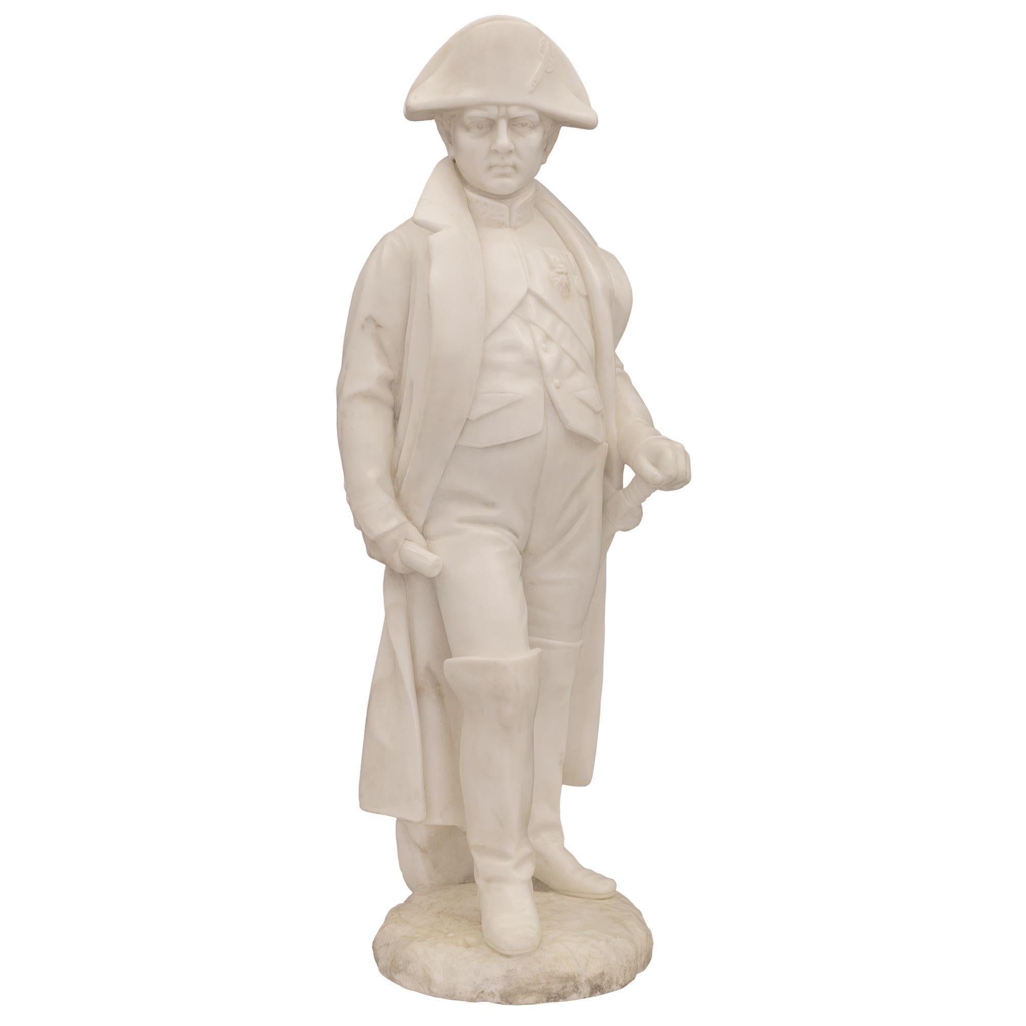 A striking French 19th century white Carrara marble statue of Napoleon. The statue is raised by a fine circular ground designed base where Napoleon is standing. He is dressed in his chasseur uniform with a wonderfully detailed flowing cloak and