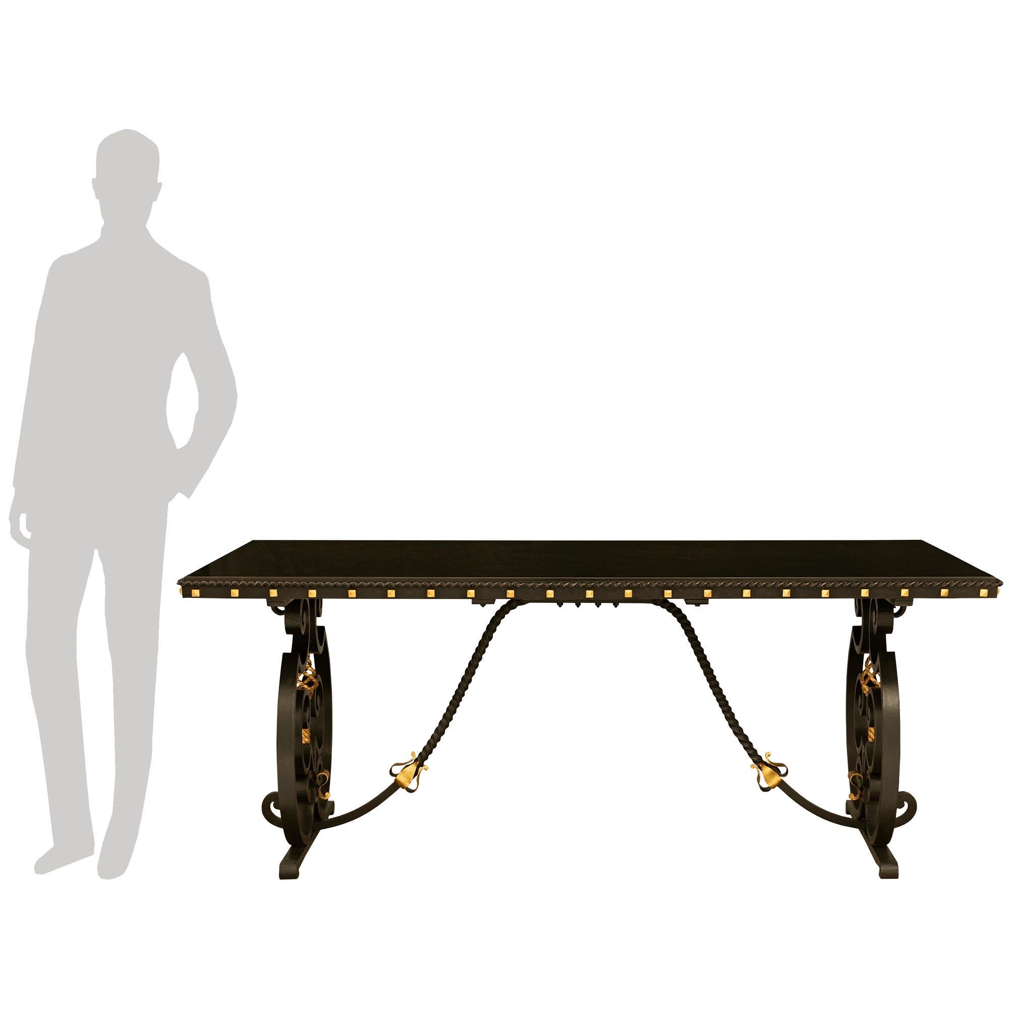 An impressive and handsome French 19th century Wrought Iron and Gilt center table. The table is raised by thick double scrolled iron supports flanking the central reserve with a gilt spiral and twisted stem. The two supports are joined by twisted