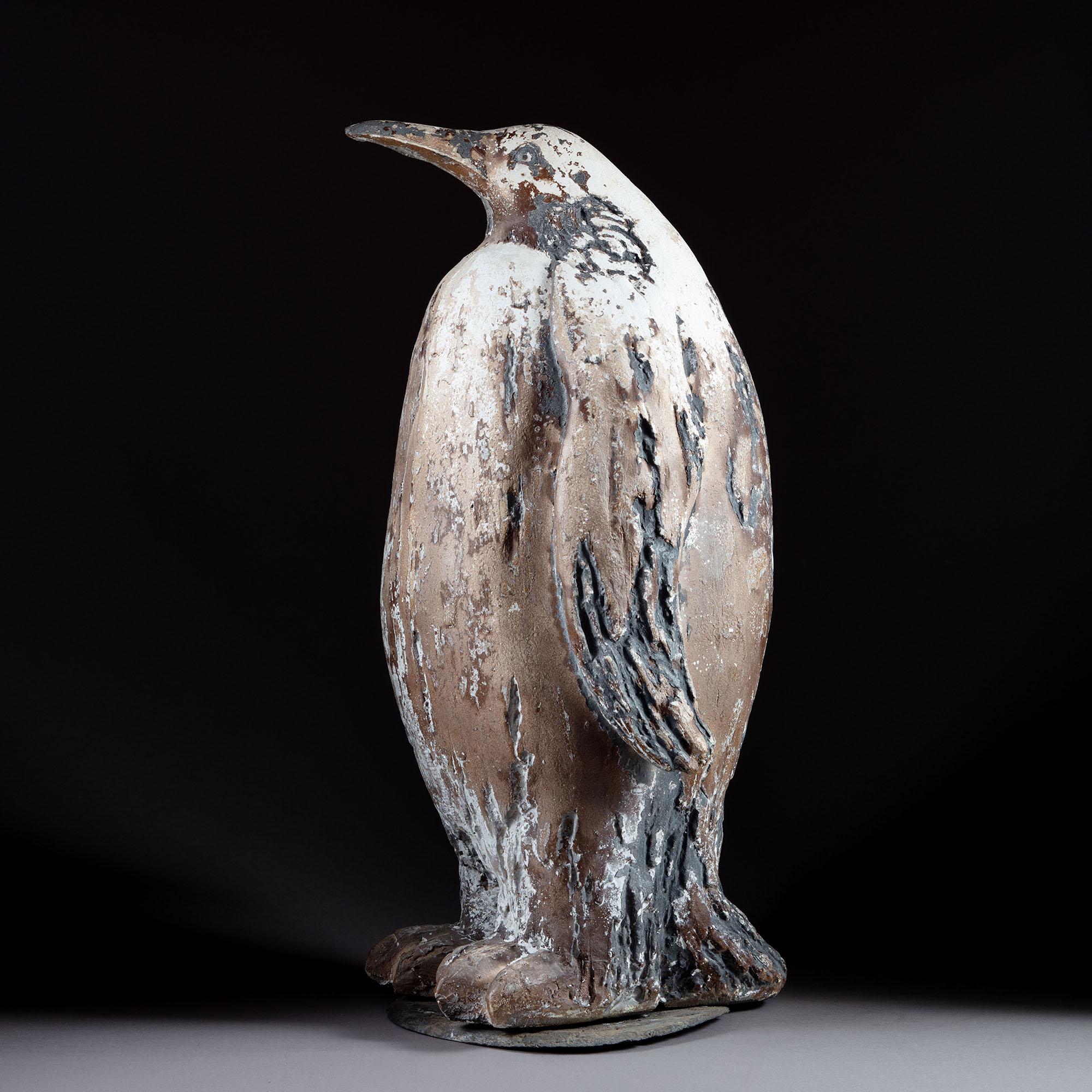 An unusual plaster sculpture of an emperor penguin with paint residue, standing on a slate base.