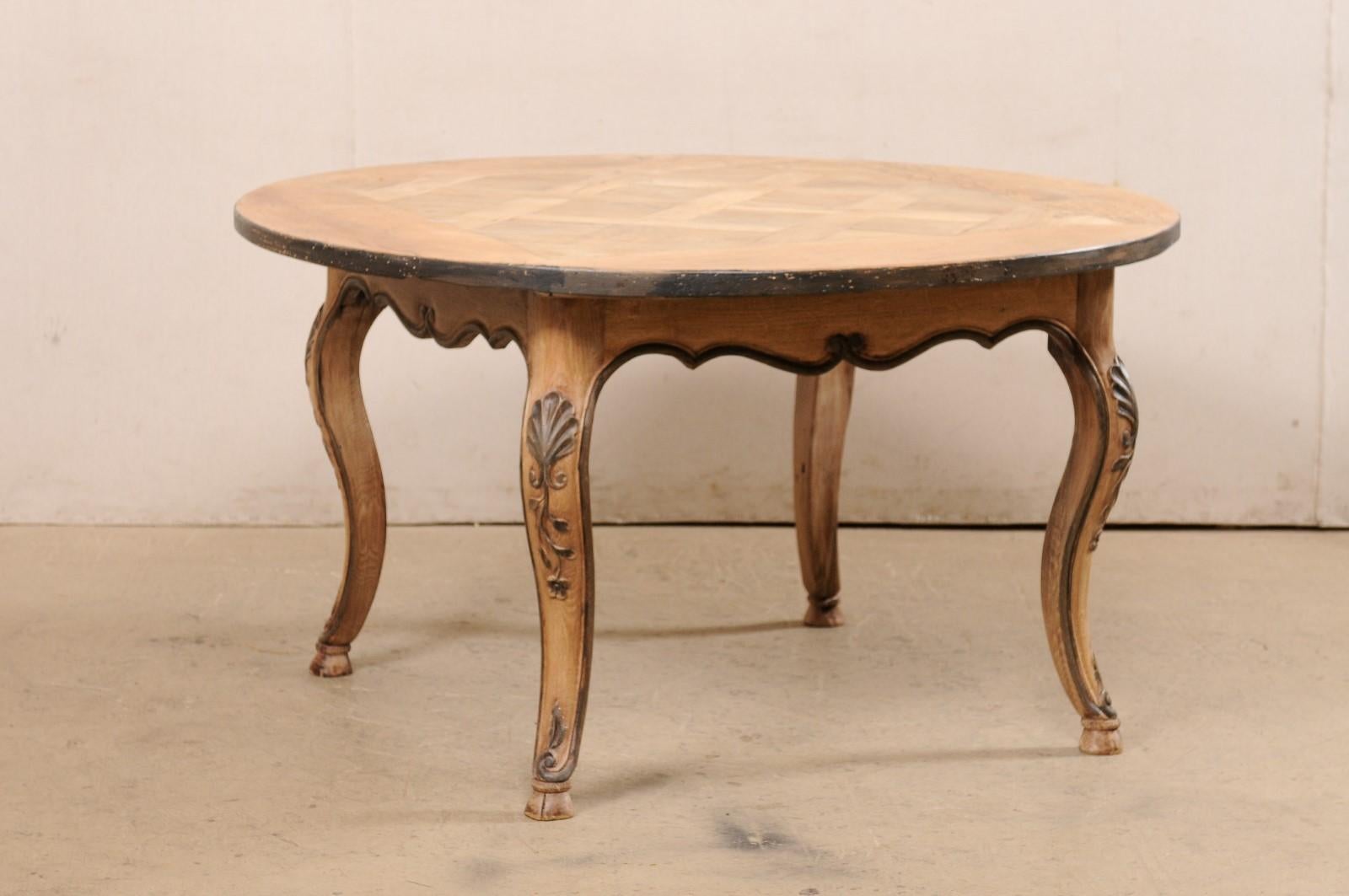 A French carved wood and round-shaped table from the 19th century. This antique table from France features a round shaped top (approximately 4.6 feet across in diameter) that has a lovely inlayed lattice inspired squared center, and overhangs the