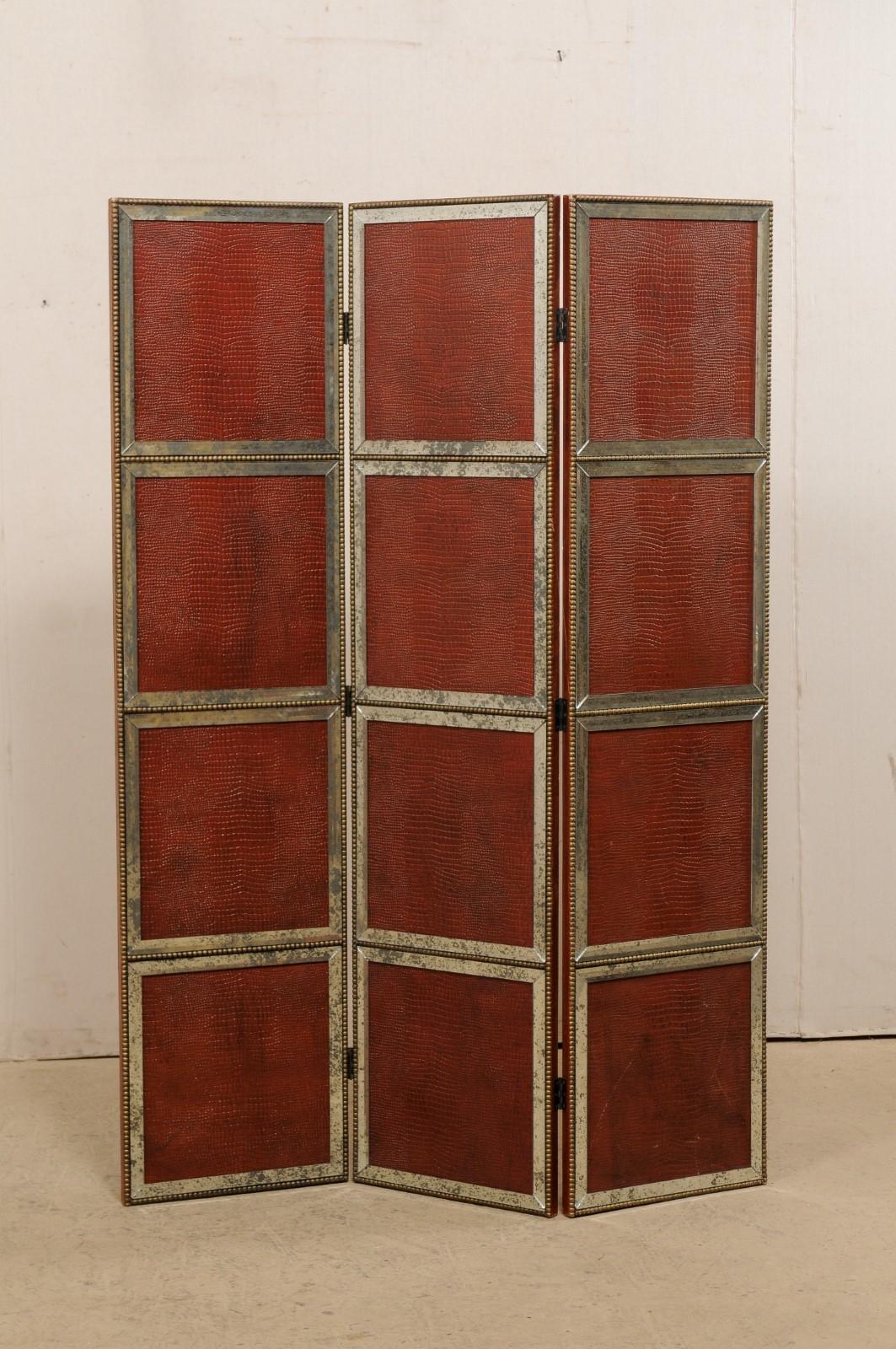 A French leather and mirrored glass folding accent screen or room divider. This vintage accordion style folding screen from France features three long sections, connected with hinges, each section comprised of four panels in a burnished red-toned