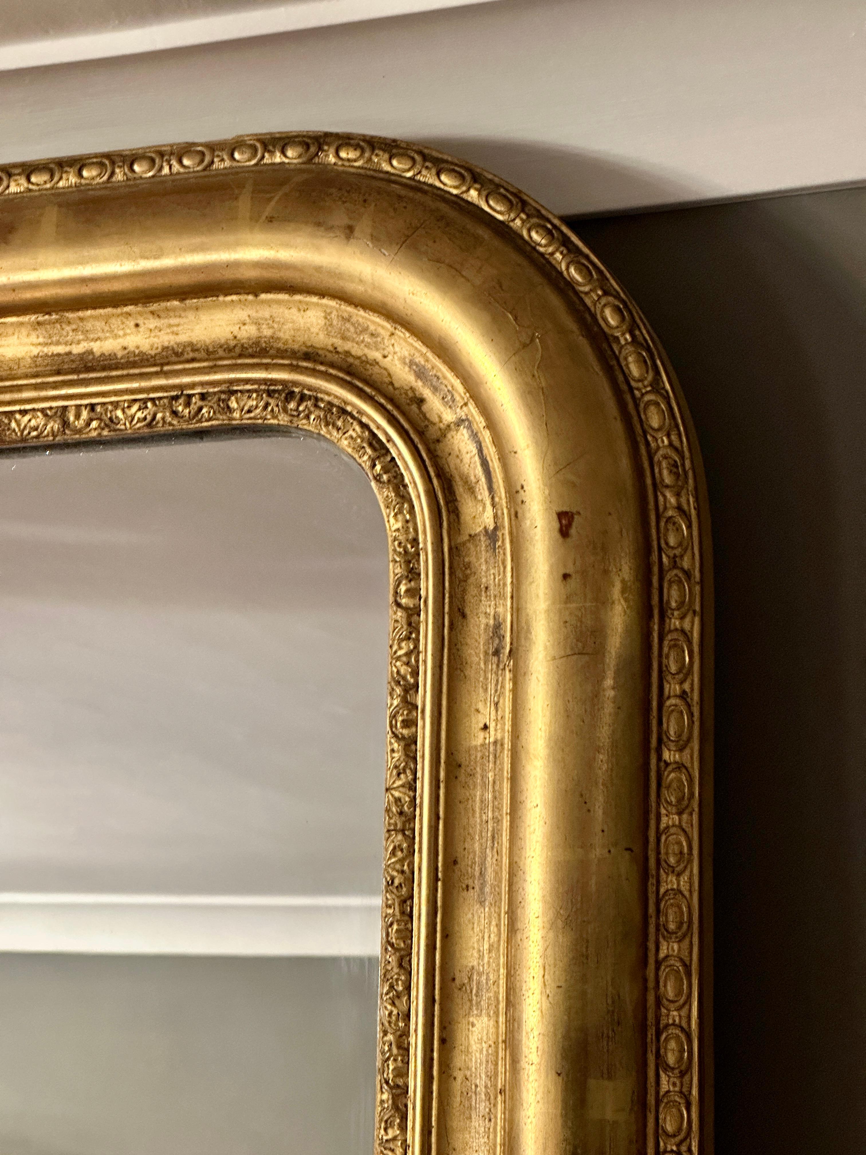 An antique domed toped gold gilt mirror with original mercury plate glass and backboards. Mid 19th century, imported from Paris. Little foxing in the mirror but overall very clear reflection. Warm patination on the gilt work, decorative frame.