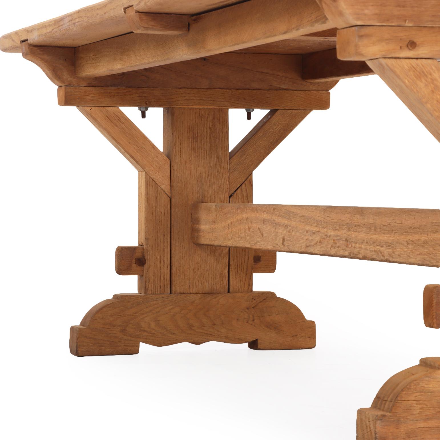 C'est une très belle table ! Une table à tréteaux substantielle et bien fabriquée, dotée d'un épais plateau en chêne soutenu par des tresses de style architectural formant des bases à tréteaux reliées par un châssis central. La construction à tenons