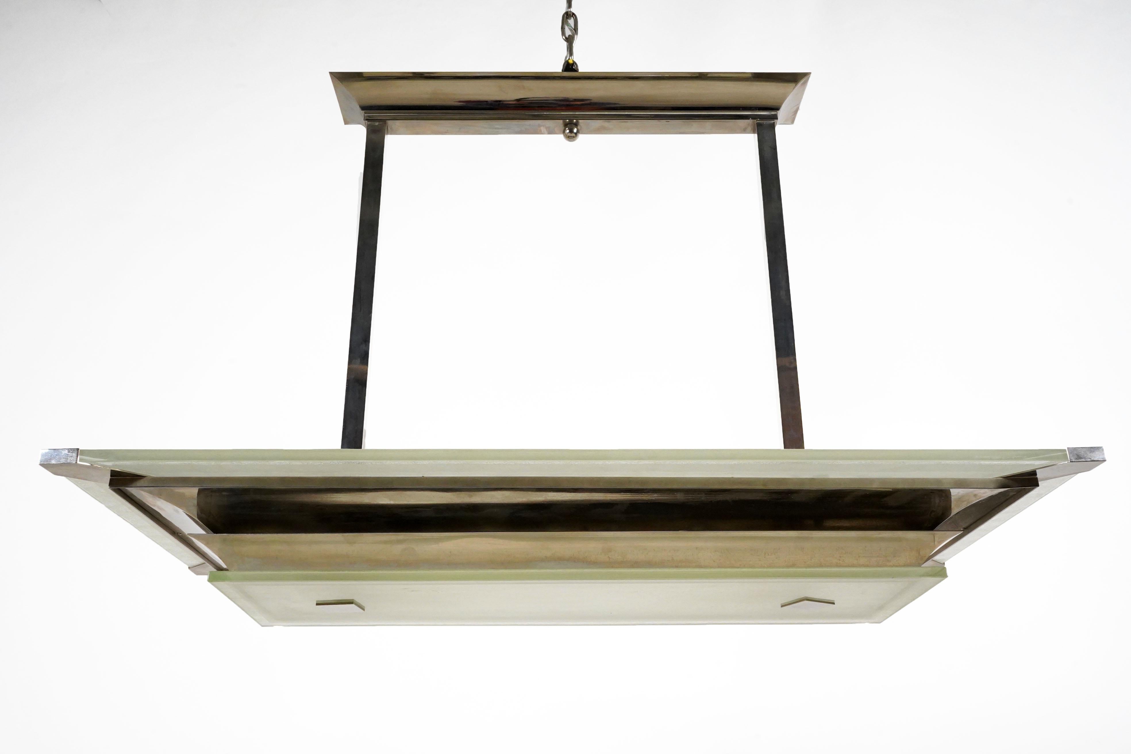 This stylish chrome and steel chandelier features dramatic sculpted curves and thick glass plates.  All parts are original -the two-level rectangular lantern frame, sizable ceiling canopy and extending arms.  The frame is made from multiple segments