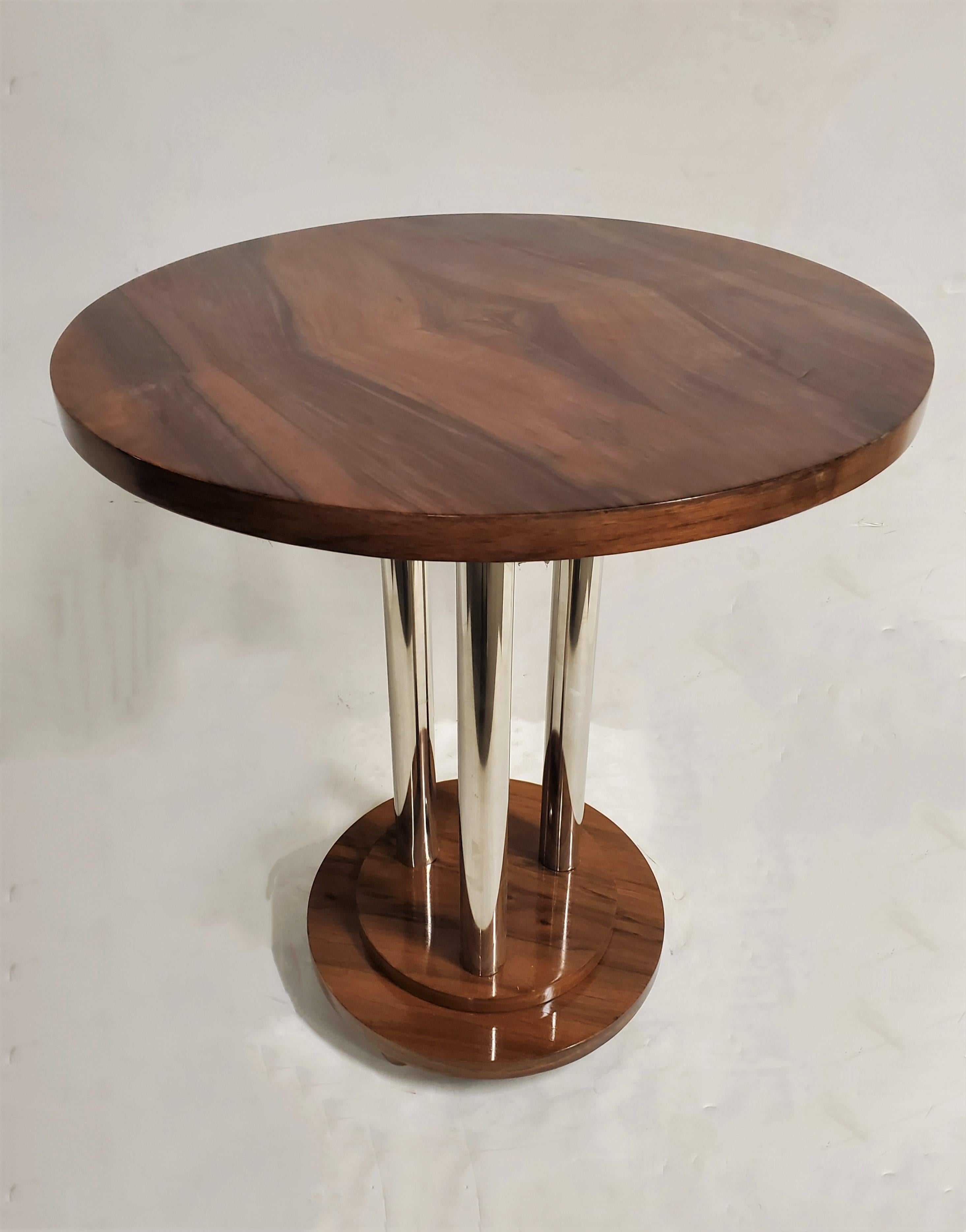 A French Art Deco walnut side table highlighted by metal accents. Three tubular metal poles support a beautifully grained, book matched circular wood top with a geometric diamond shape pattern, that rest on a circular stepped base ending with small