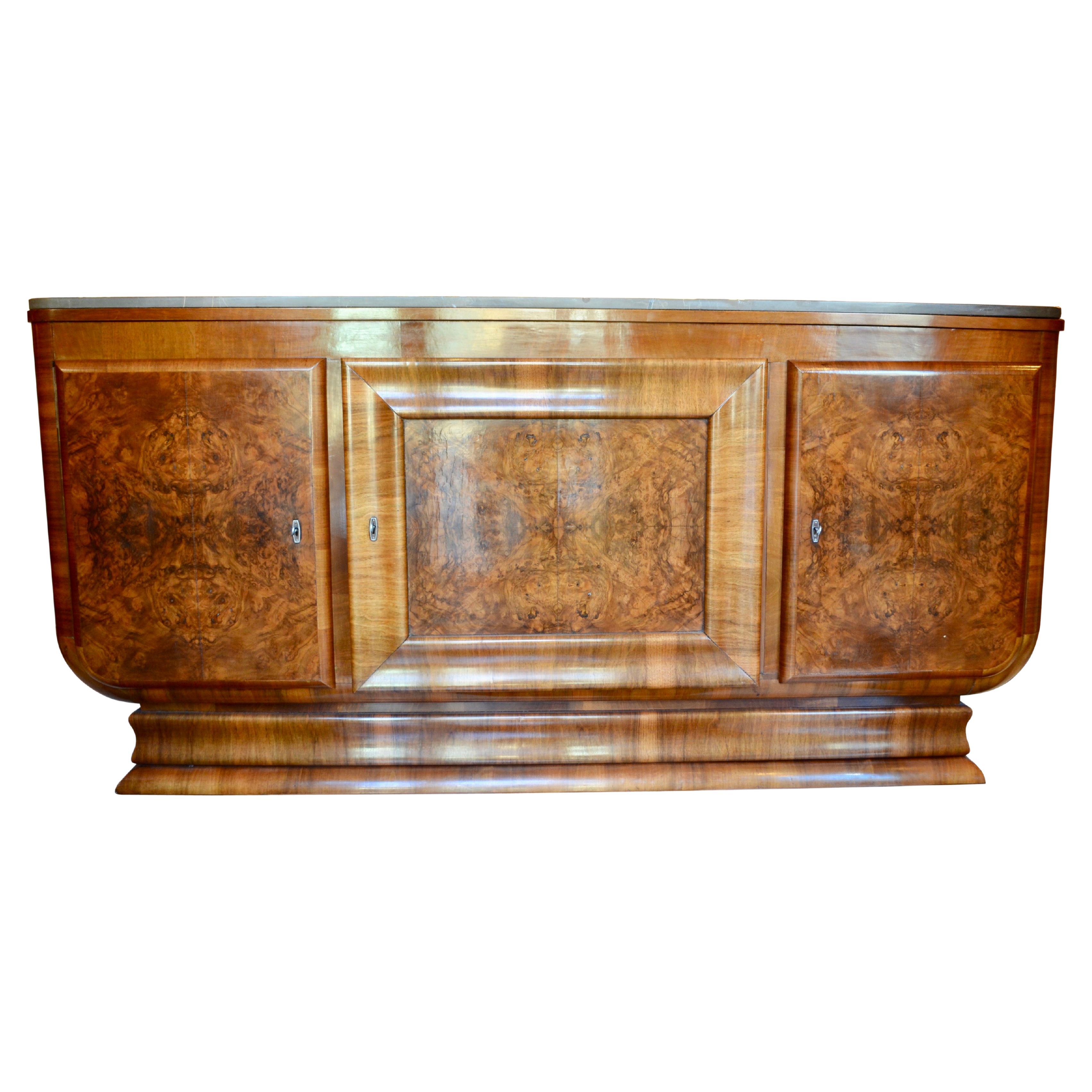 This is a classic three door 1930's French Art Deco sideboard or buffet in matched burl walnut veneered finish. The two side doors open to reveal a shelved interior and a top drawer. The larger central compartment opens to a simply shelved interior.