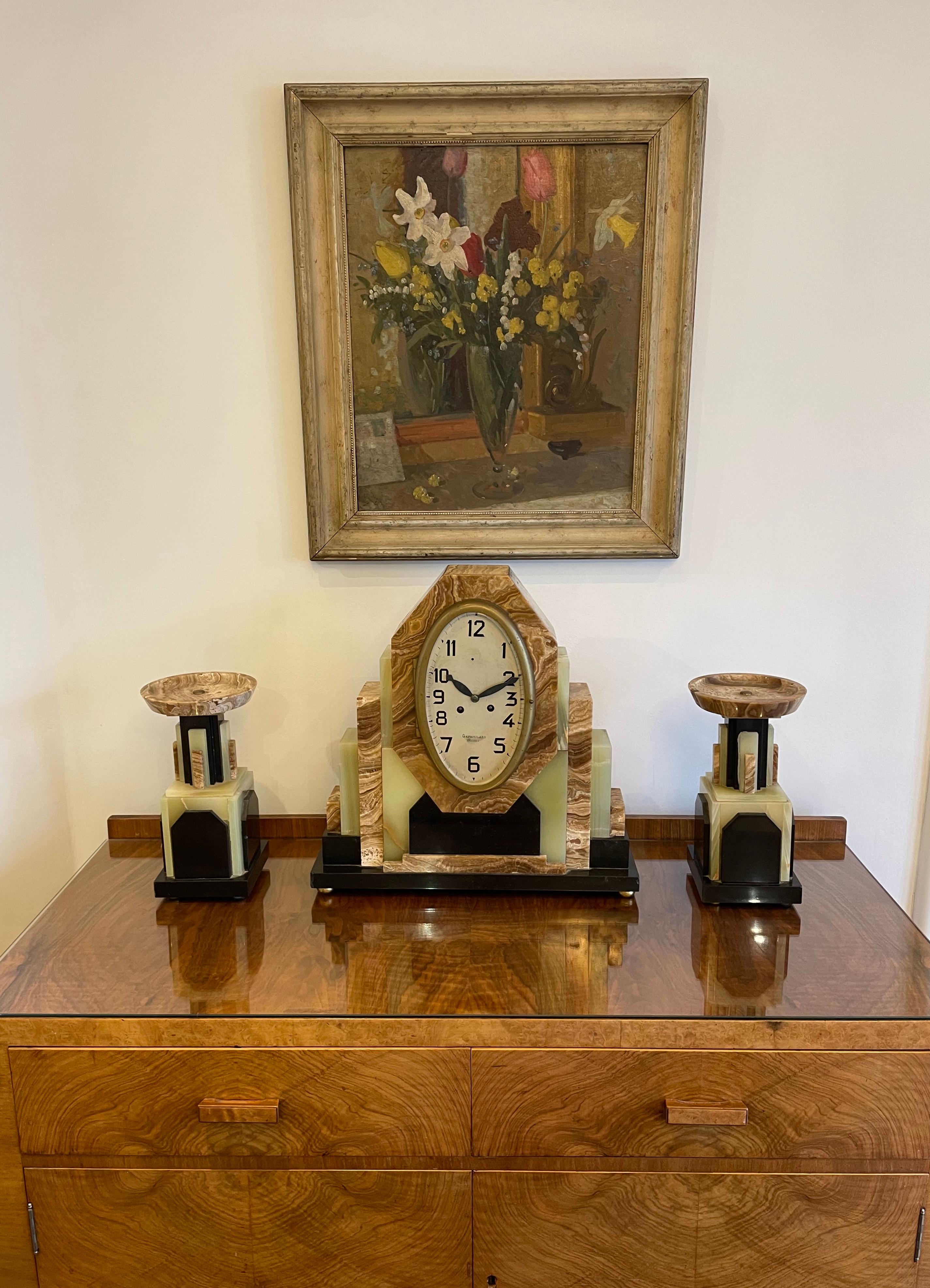Eine große französische Art-Déco-Uhr mit einem Paar passender Garnituren. Das ovale Zifferblatt mit sehr guten schwarzen Art-Deco-Ziffern und -Zeigern, einem versilberten Zifferblatt und einer Messinglünette. Das Zifferblatt trägt die Aufschrift