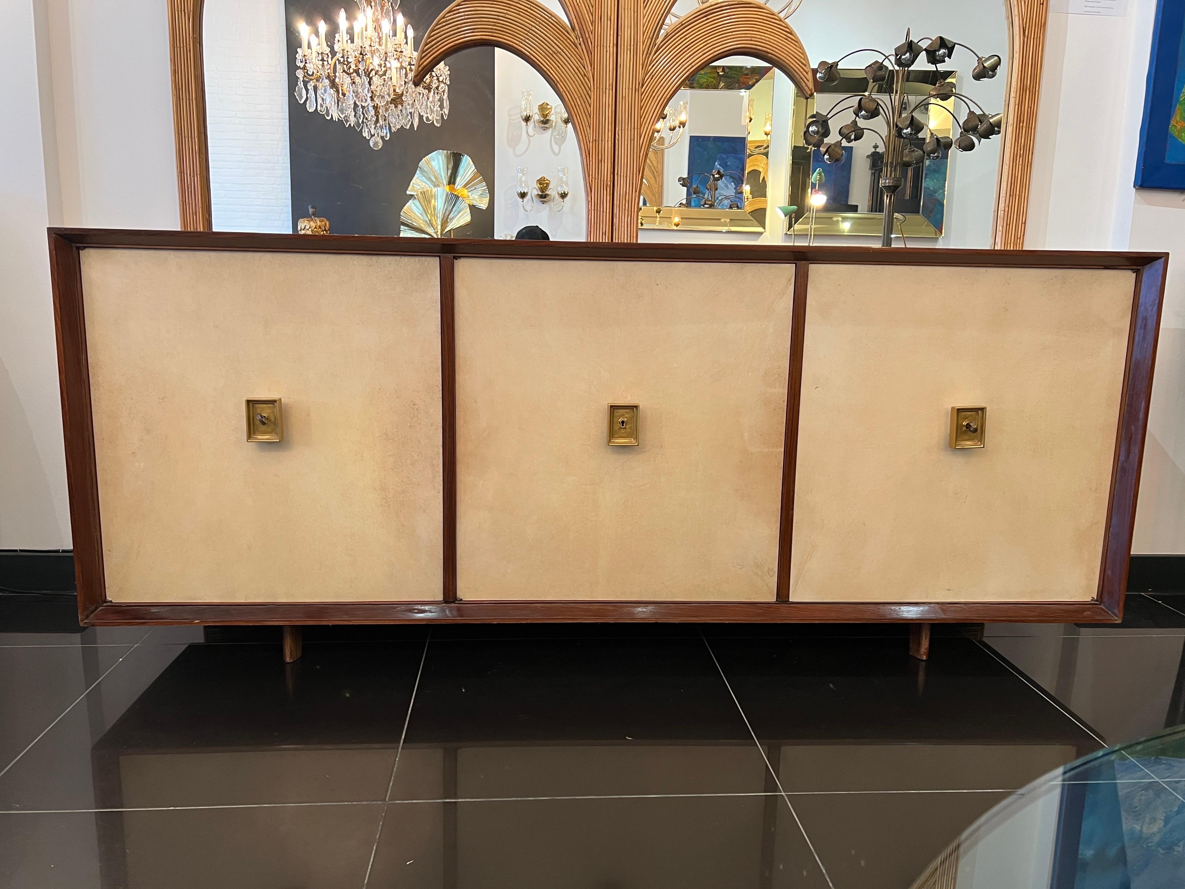 A rare French Art Deco sideboard made from parchment and solid wood with gilded bronze handles. The sideboard has 3 doors with one housing 4 large drawers and the others each has a single adjustable shelf. The design is attributed to Jacques Adnet.