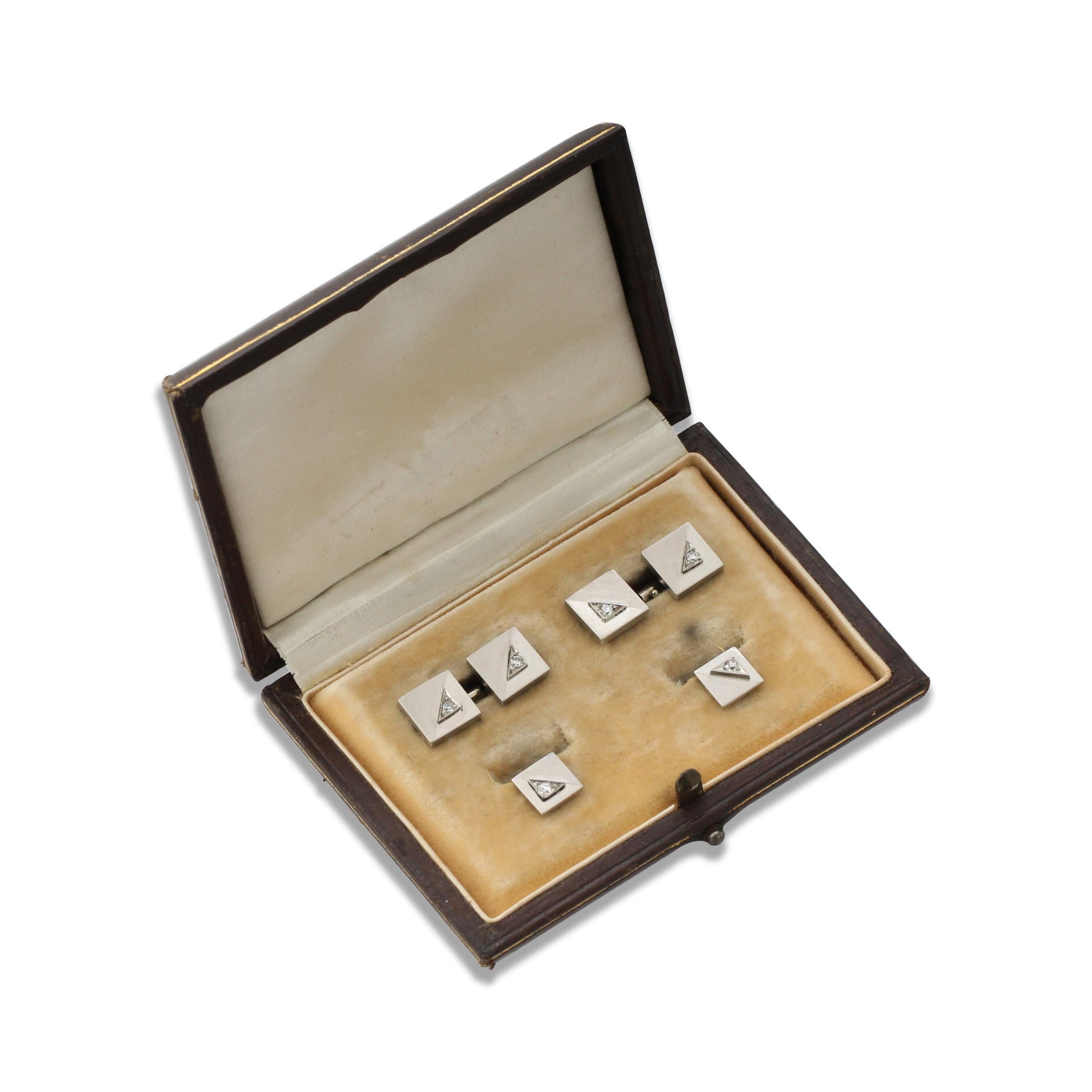 A platinum and diamond Art Deco set of Cufflinks and Studs. Each side is set with a single diamond and a square design with a brushed finish across half of each square. Origin: French. With a Fitted Box.