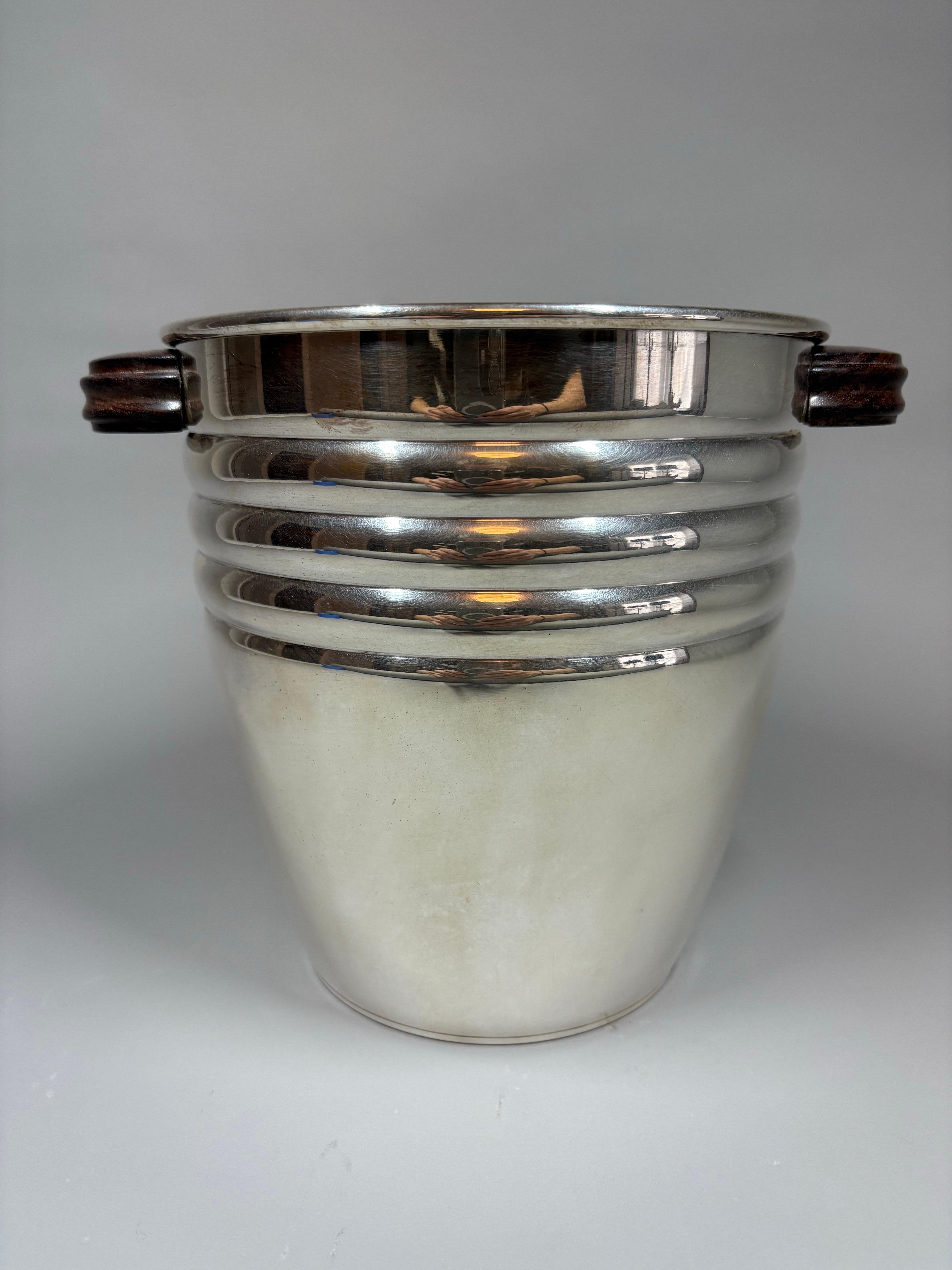 Versilberter Champagner-/Weinkühler aus der Zeit des französischen Art déco mit handgeschnitzten Griffen aus Palisanderholz. Der Körper des Kühlers horizontal gerippt wie die Enden der halbkreisförmigen Griffe.
Paris