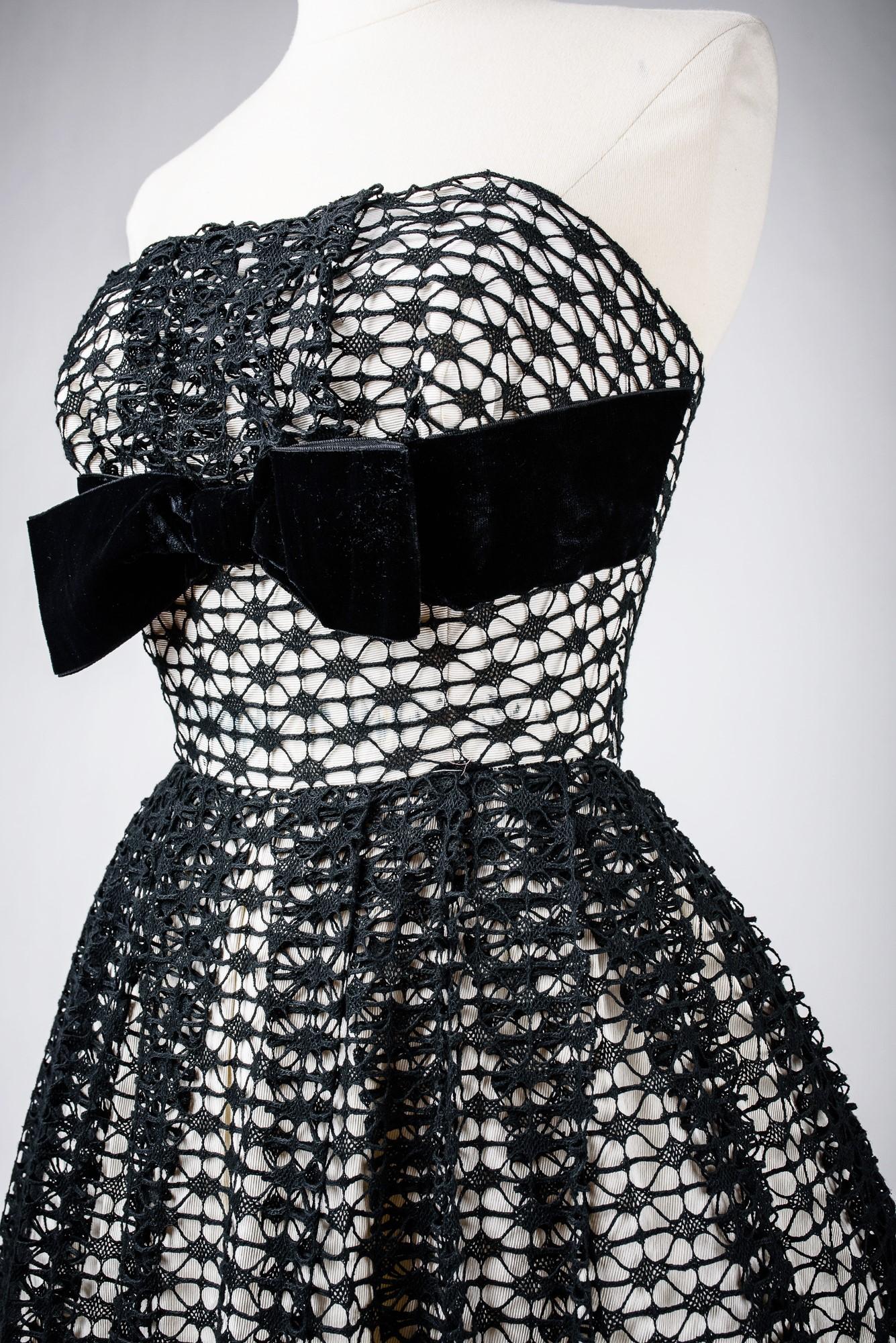 Circa 1950

France

Beautiful silk and lace ball gown or ceremony dress, black and white dating from the 1950s. White silk faille bottom entirely covered with black cotton lace, handmade with a spindle and highlighted with two large black velvet