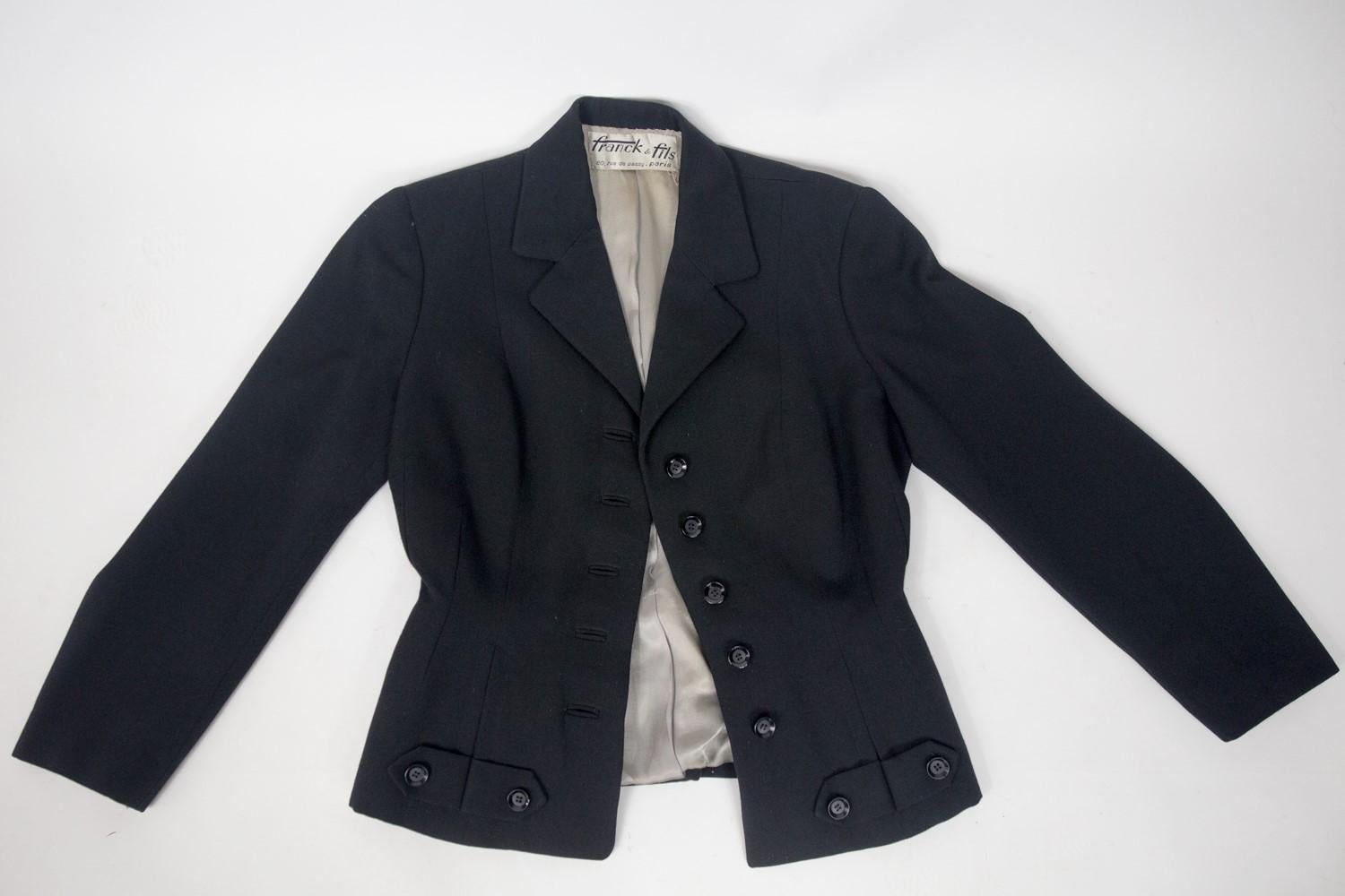 Circa 1945/1950
Paris France

Bar skirt suit by Franck & Fils in black woolen cloth in the tradition of Christian Dior's New Look and dating from the end of the 1940s. Fitted jacket with structured cut and marked waist hugging the hips. Crossed