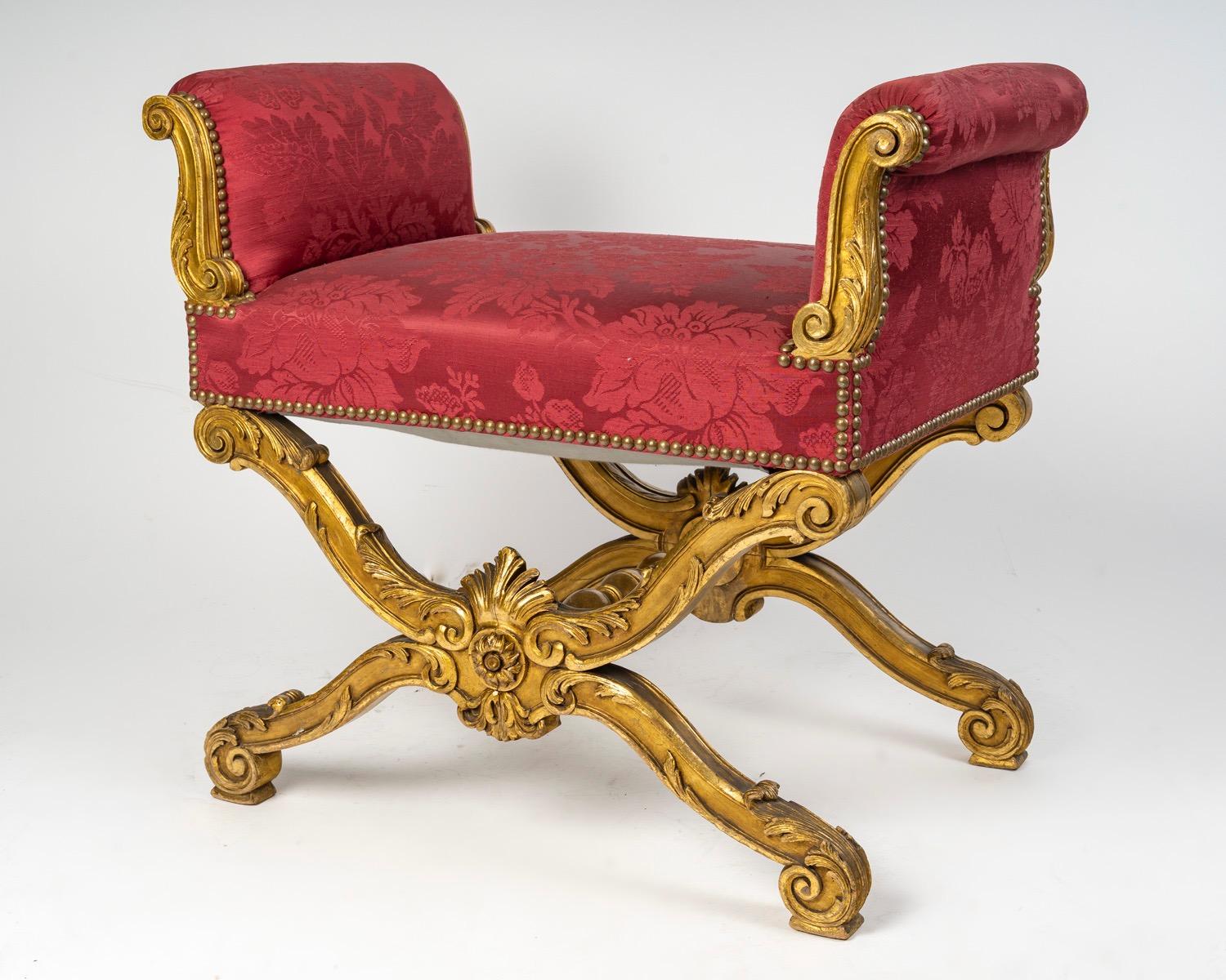 Uno sgabello francese Belle Époque a forma di Curule con braccioli 
Legno dorato riccamente intagliato con volute, conchiglie e foglie d'acanto 
Tappezzeria damascata rossa in perfette condizioni 
Stile Luigi XV 
Circa 1890

L'eclettismo del Secondo