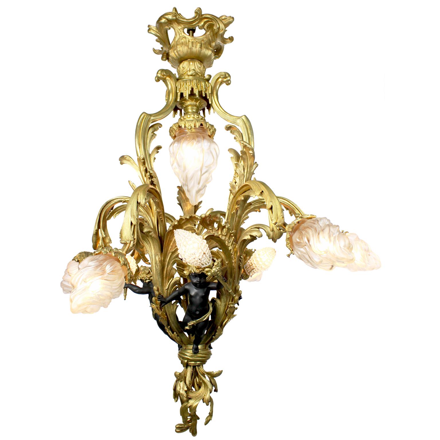 A very fine and rare French Belle Époque gilt bronze and ebonized-patinated bronze ten-light cherub chandelier, with three winged cherubs, each holding a flame light with beaded glass bulb covers, the six outer lights with frosted glass flame shades