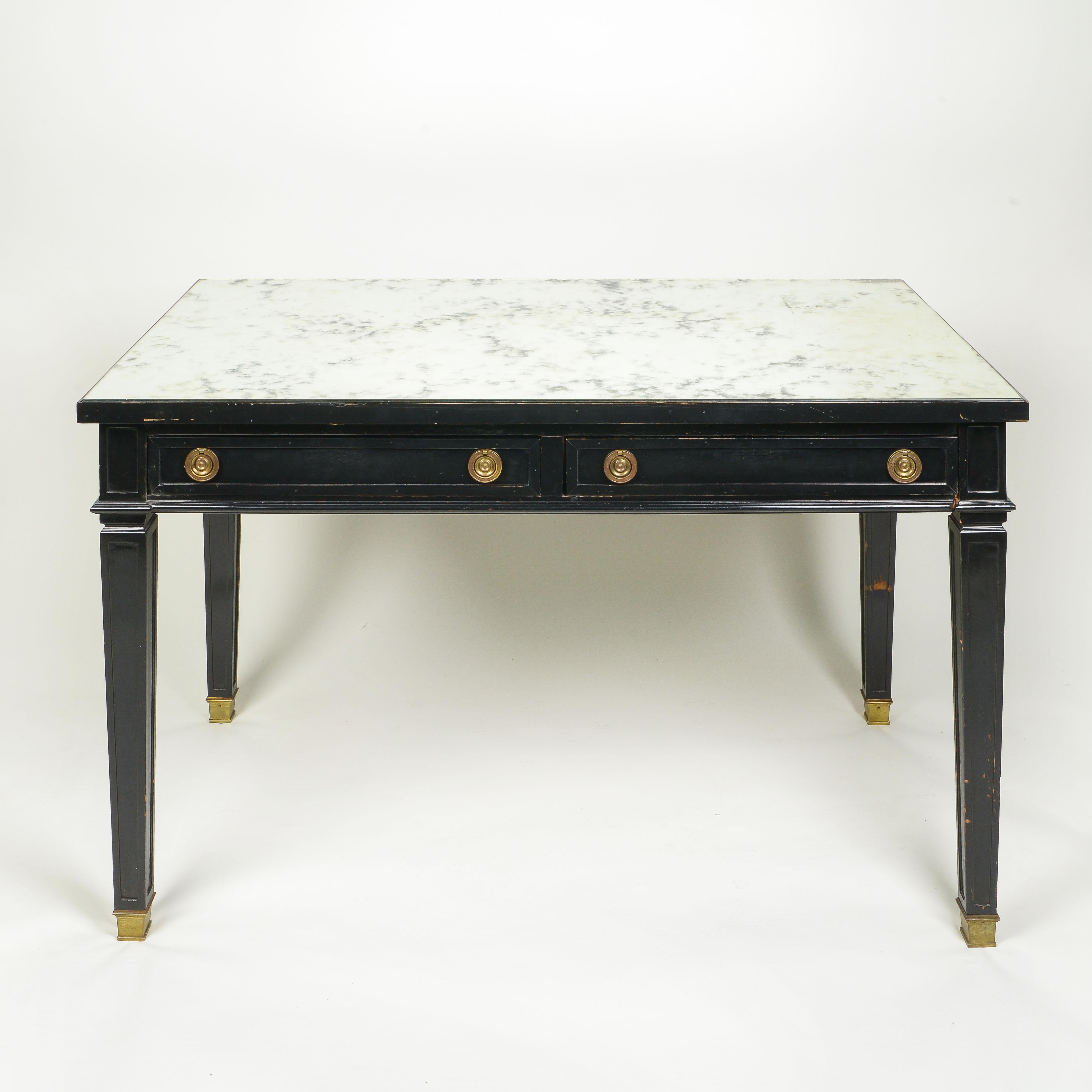 The rectangular top inset with antiqued mirror glass over two frieze drawers; raised on square tapering legs terminating in brass sabots.
