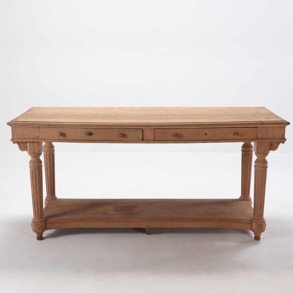 French bleached oak drapers table C 1880. This piece would make a perfect center island in your kitchen. It has a shaped botttom shelf and two drawers on one side. The piece is finished on both front and back side. There is a slight bow to the top.