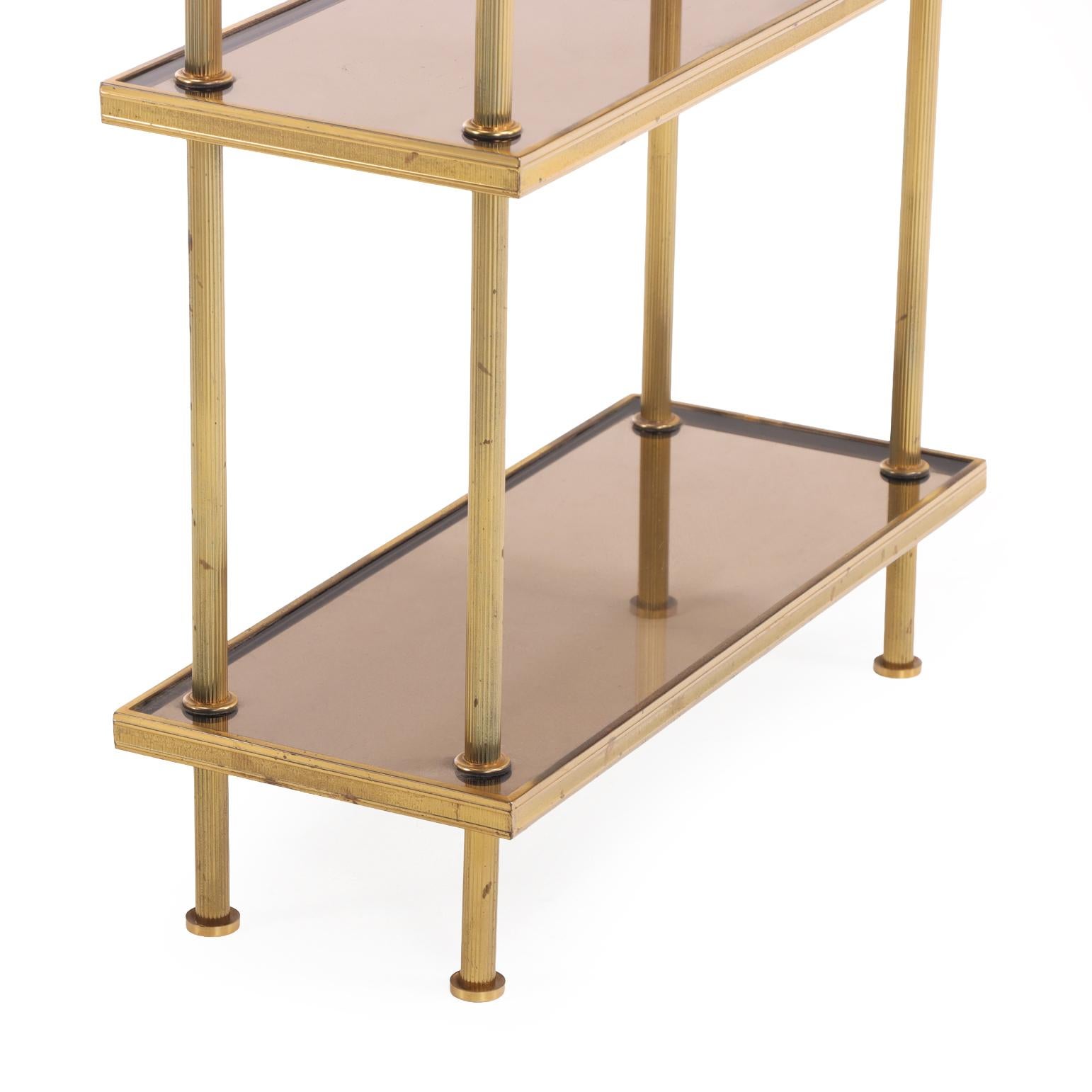 Elegant mid-century French three-tier table featuring a brass frame fitted with smoked glass shelves. Each shelf measures a slim 8
