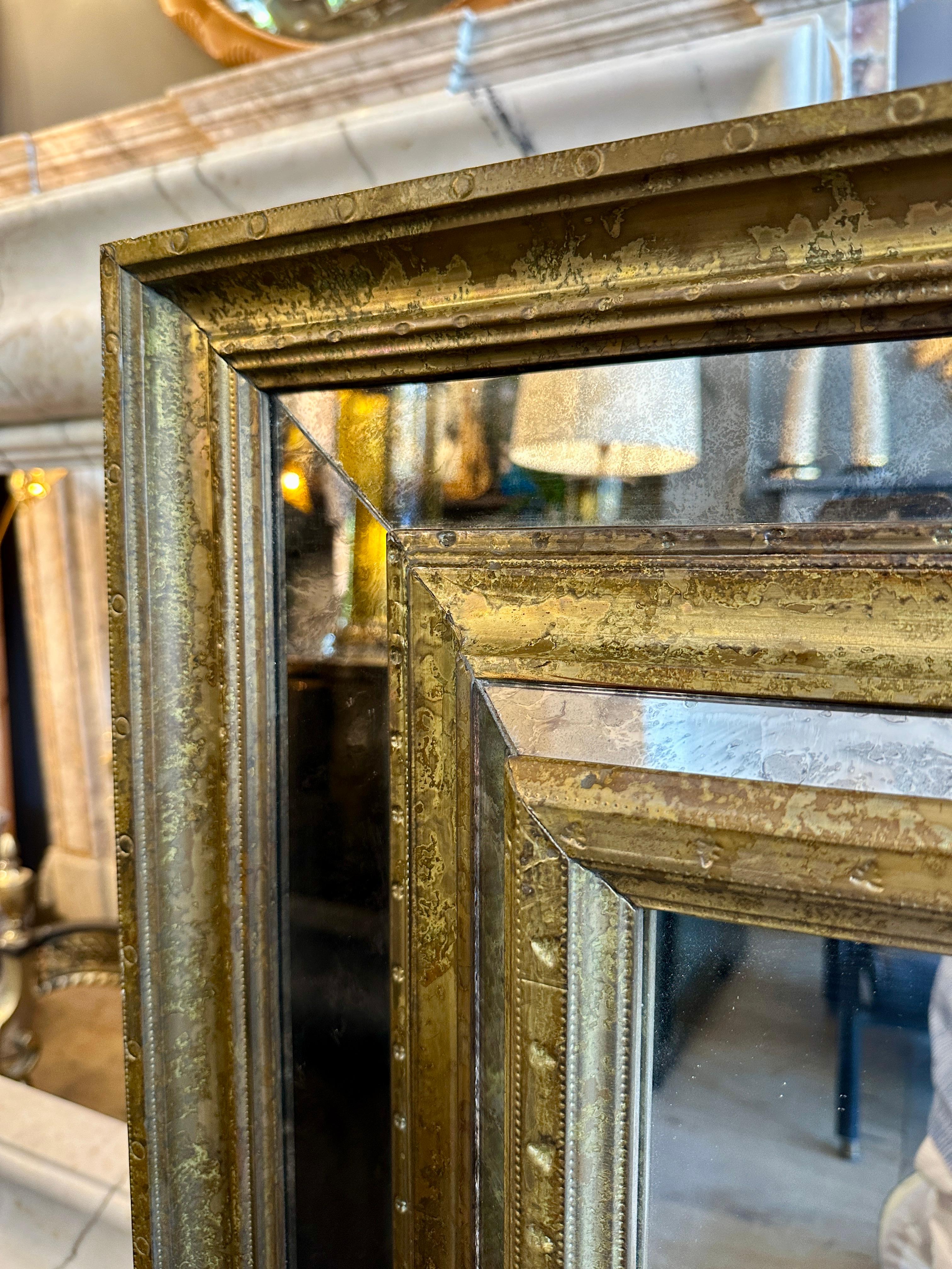 Specchio a cuscino con cornice in ottone patinato e consumato, dettagli rivettati, bordi a specchio invecchiati e piastra centrale trasparente. Può essere appeso sia in orizzontale che in verticale come nelle immagini. Cornice in stile Repousse ma