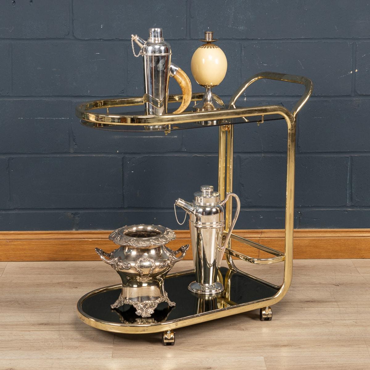 An elegant two-tier drinks trolley made in France around the 1970s. This functional piece of furniture has a smoked glass shelf to the upper level whilst on the lower level the glass has an almost black-finish mirror and a small area for holding