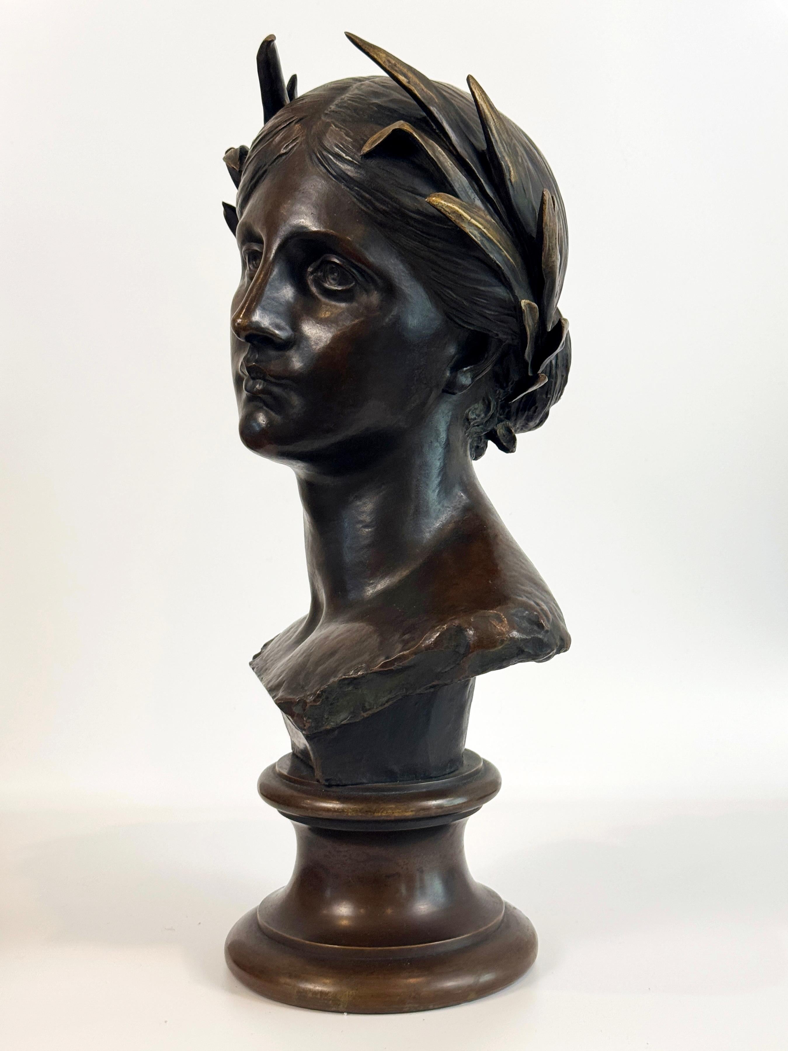 Un busto in bronzo francese che raffigura una donna classica dalle forme eleganti, coronata da una corona d'alloro. Il busto presenta una ricca patina marrone che rivela sfumature dorate sulle punte della corona d'alloro. Firmato sul retro. Si
