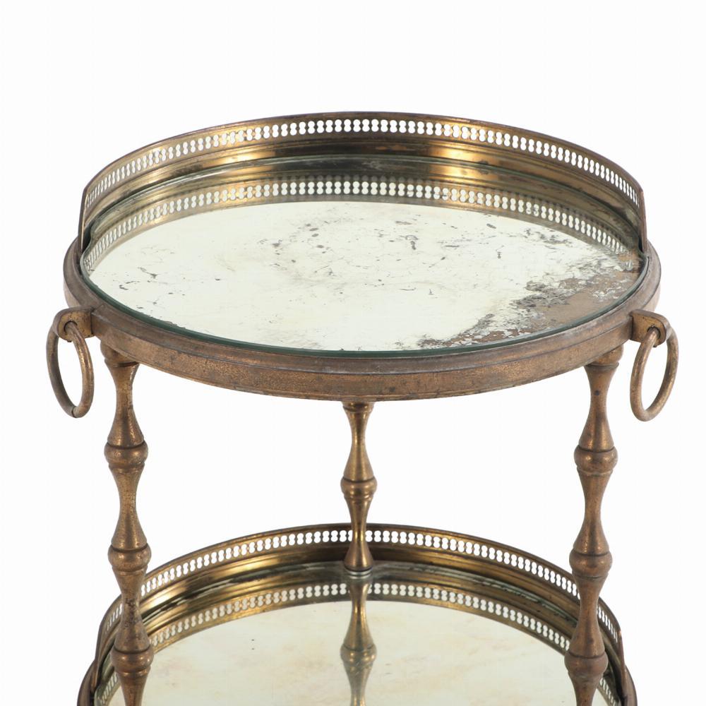 The round top with inset mirrored glass with a galleried back edge and ring decoration, supported by by three round, tapering legs joined by a conforming lower glass shelf and terminating in small ball feet. This rare table has nice wear to mirrors